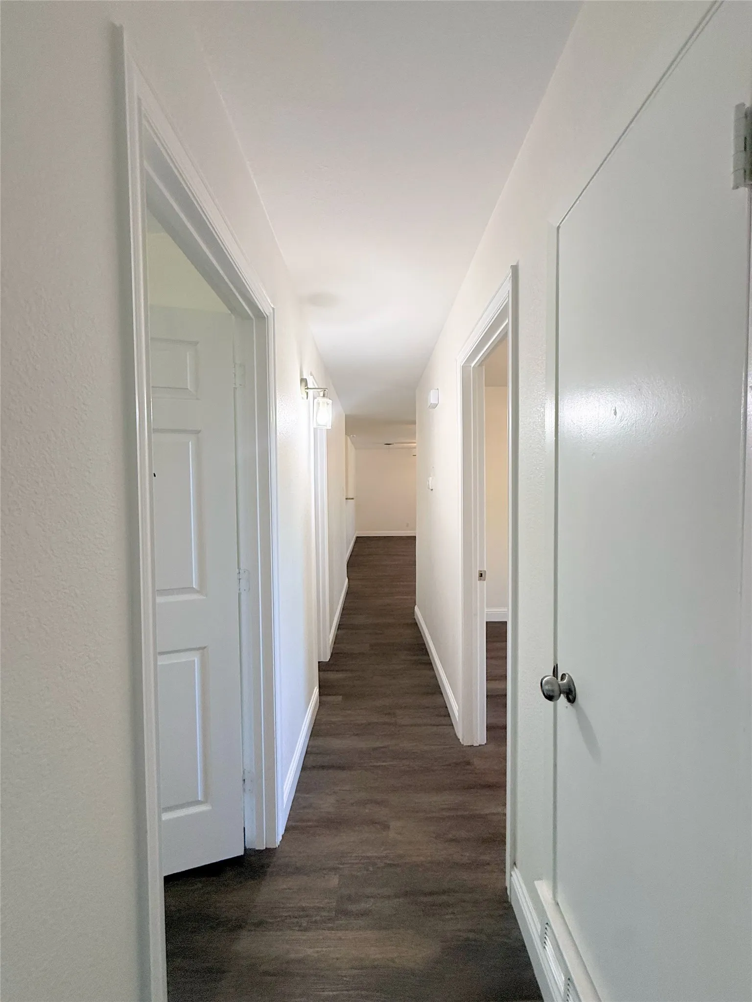 Hallway featuring wood-finish flooring, white walls, and recessed lighting