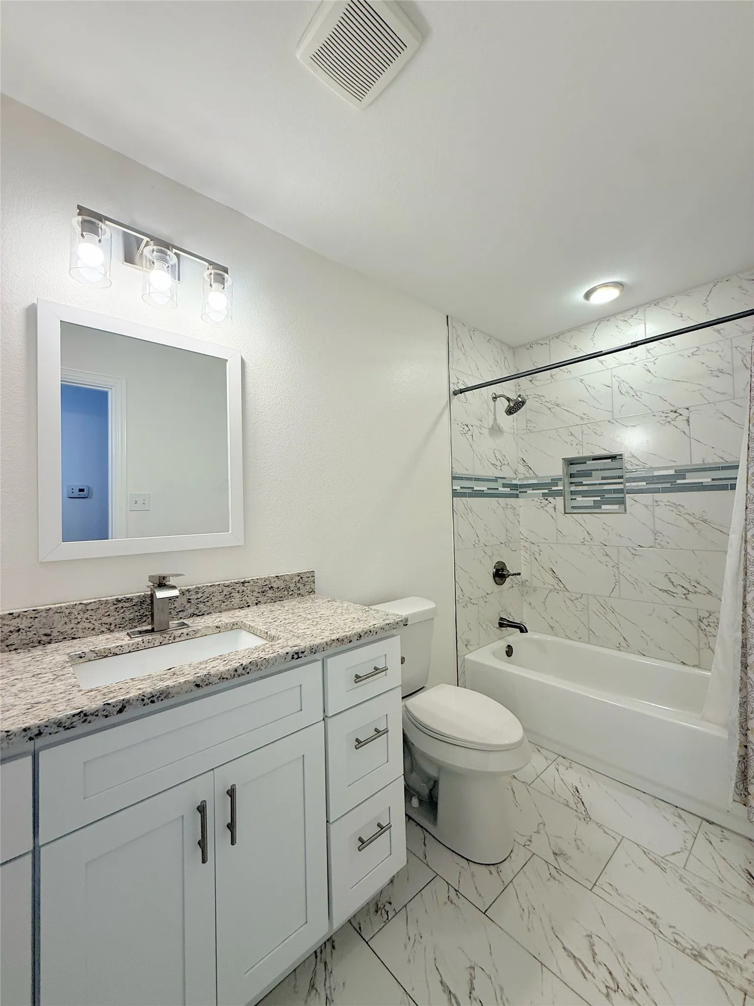 White vanity with an integrated sink and speckled countertop, featuring a chrome faucet