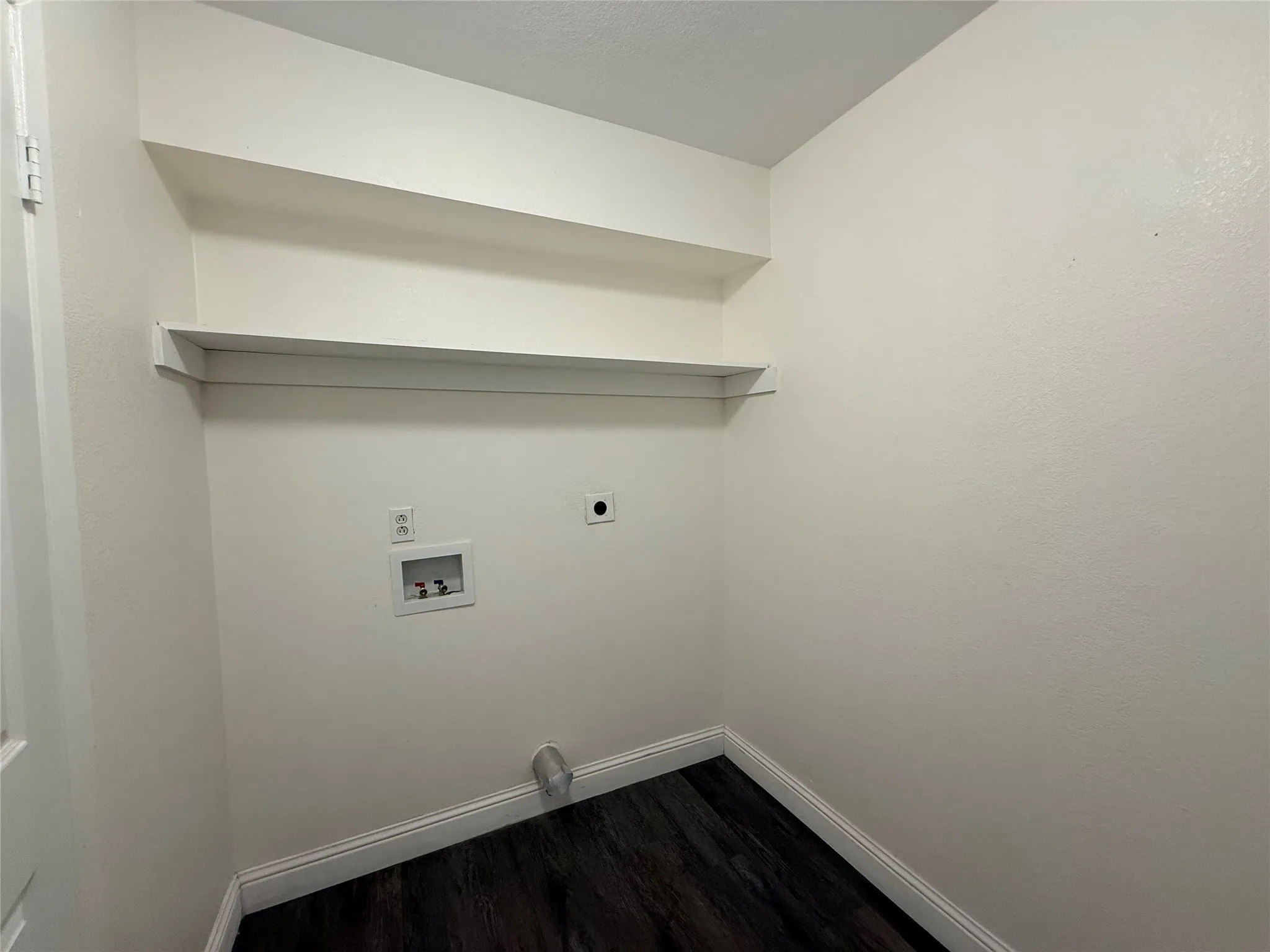 Laundry area featuring built-in shelving and wood-finish flooring
