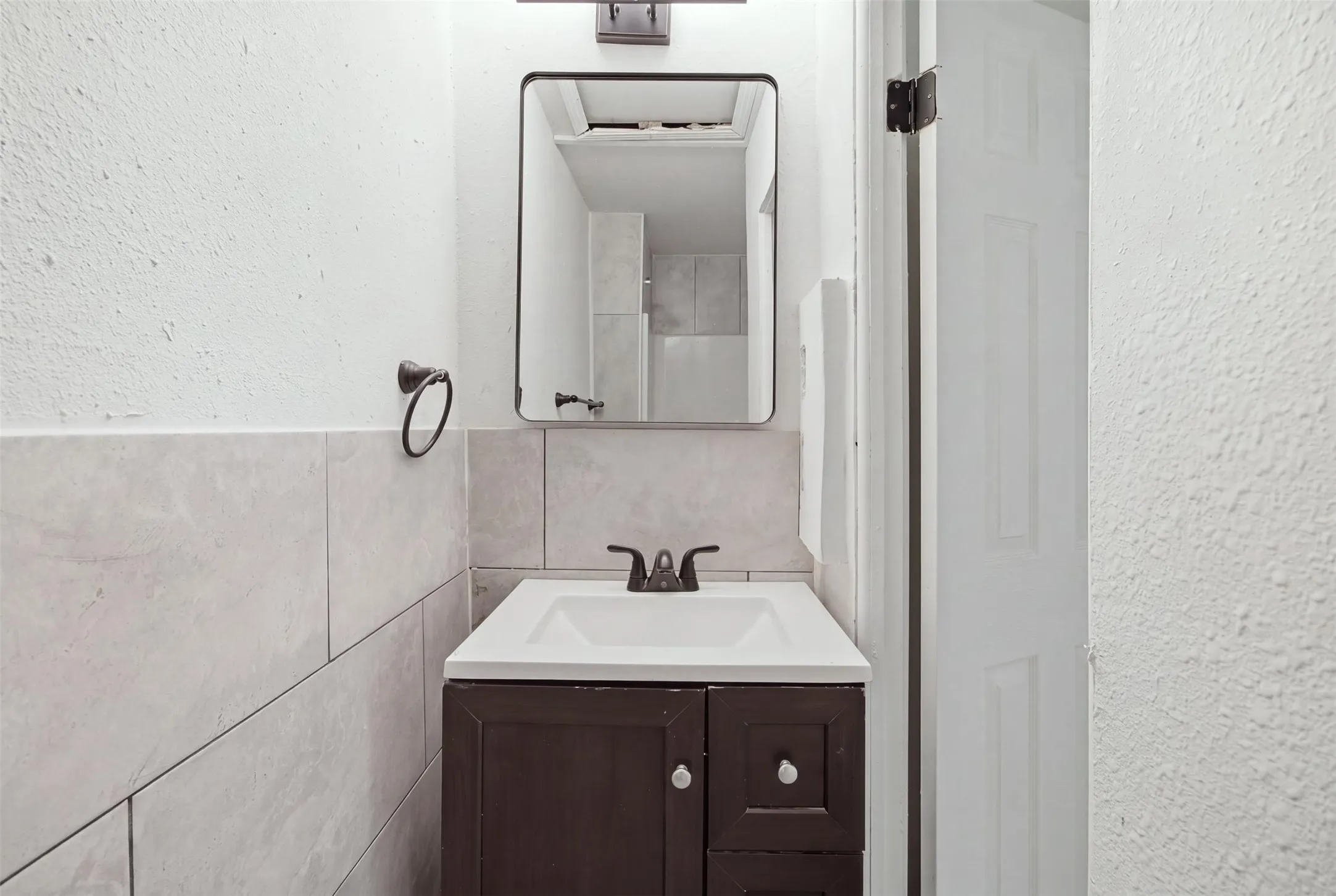 Vanity with integrated sink, dark wood-finish cabinetry, and dark bronze-finish faucet