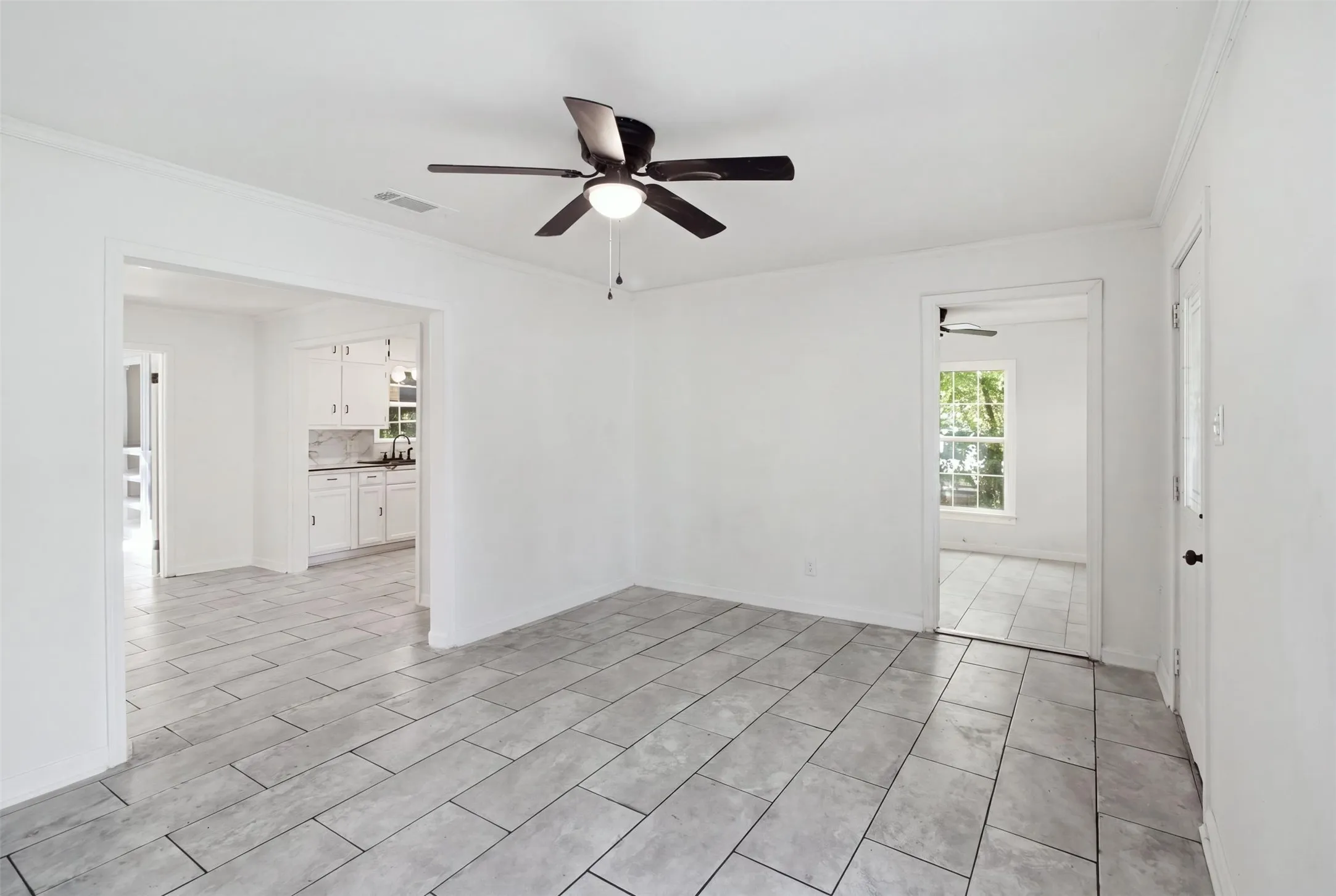Recessed lighting, ceiling fan, tile flooring, white cabinetry, and a window for natural illumination