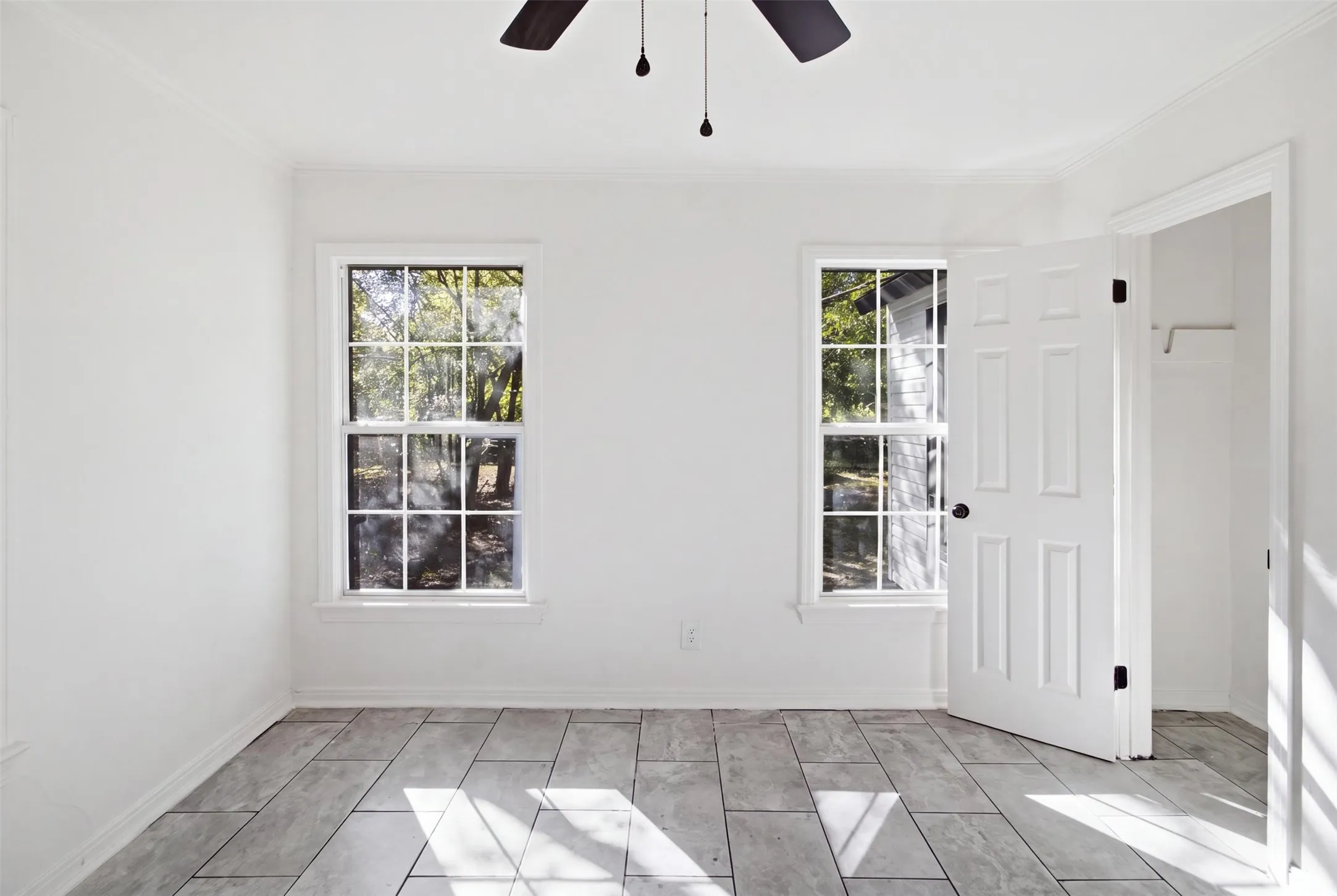 Tile flooring, two multi-pane windows, ceiling fan, and crown molding