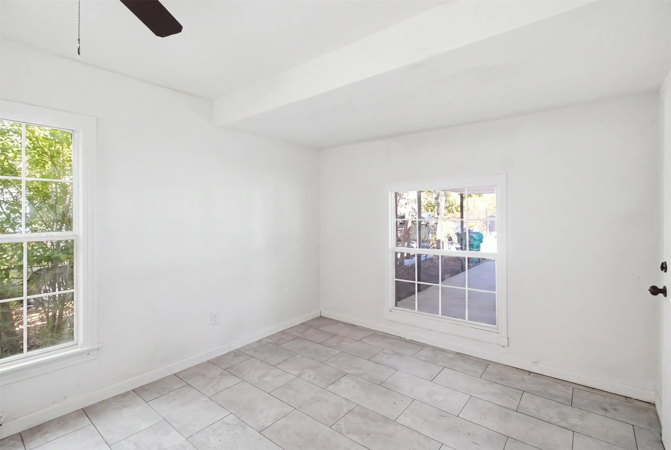 Light tile flooring with a neutral finish, multiple windows with grid panes, and a ceiling fan