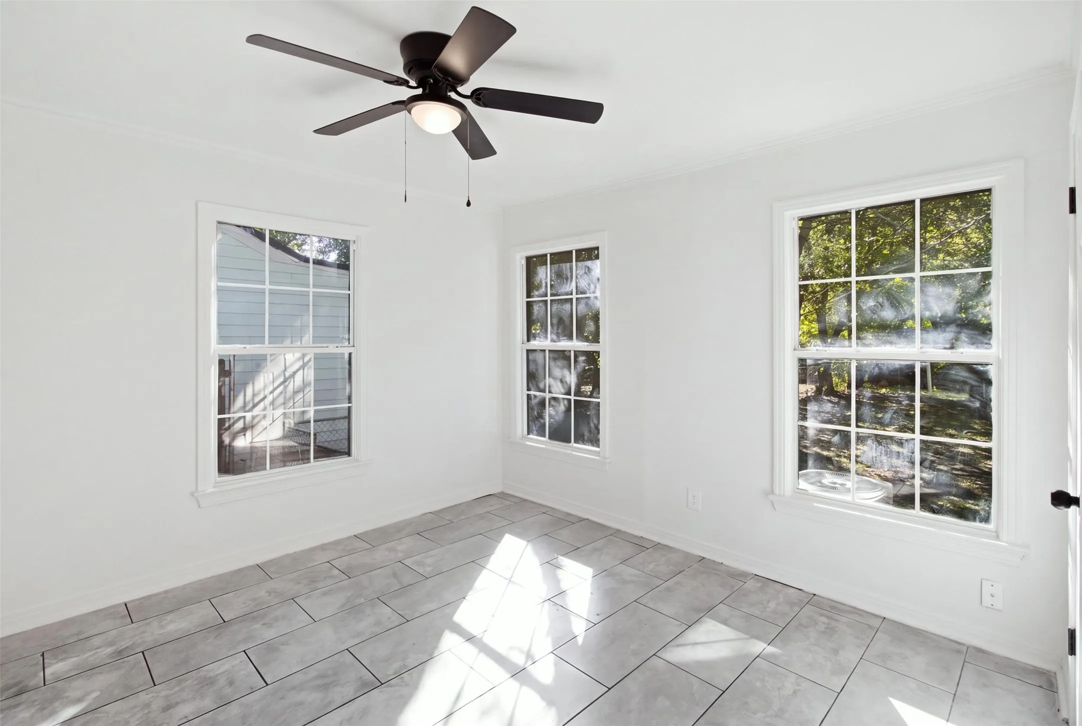 Rectangular tile flooring, multiple double-hung windows, and a ceiling fan with integrated lighting