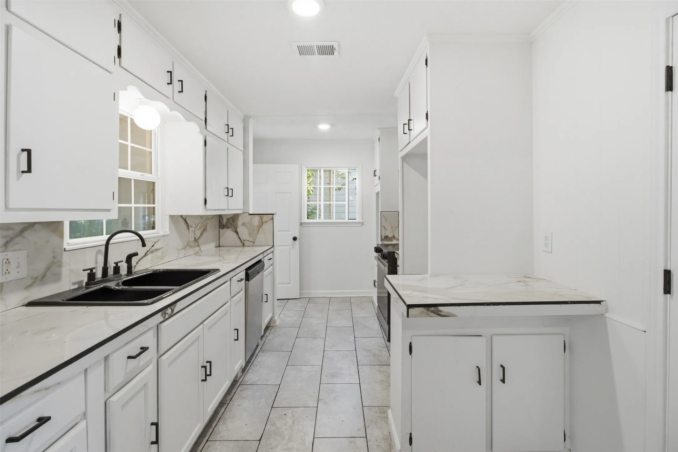 White cabinetry with black hardware, complementing black sink basins and faucet