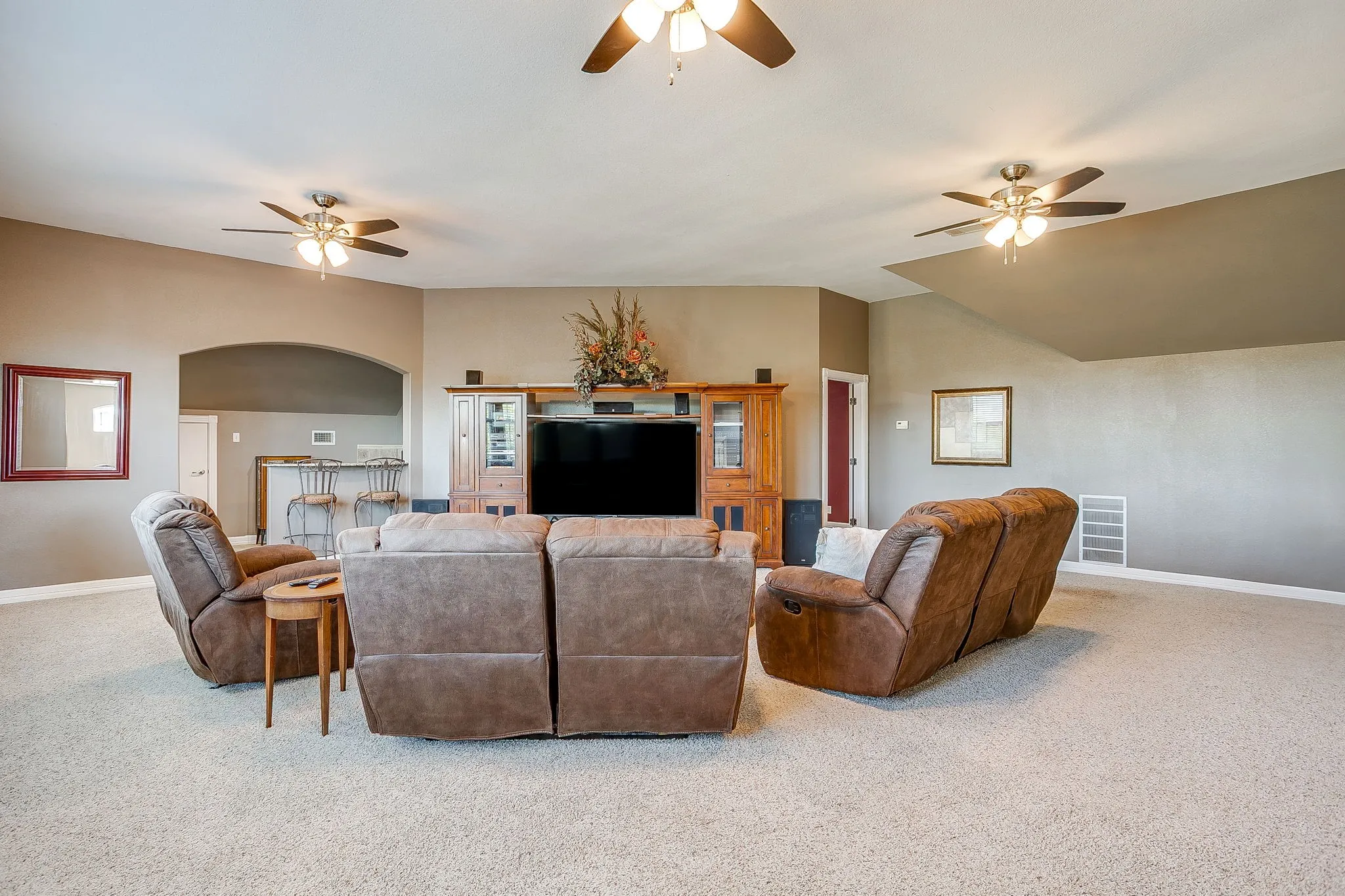 Spacious room with sloped ceilings and light-colored carpeting