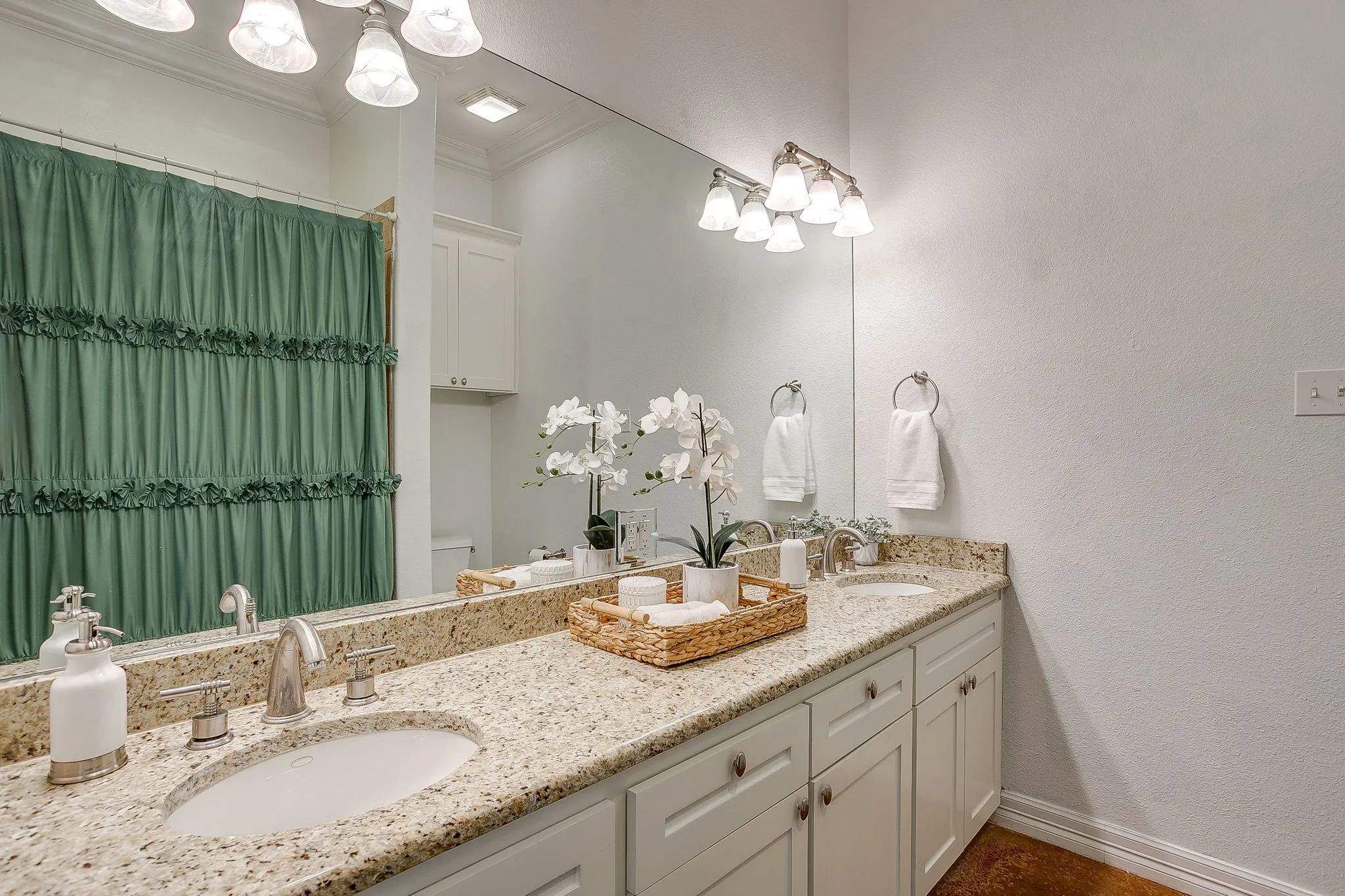 Dual vanity with undermount sinks, speckled stone countertop, and brushed nickel fixtures