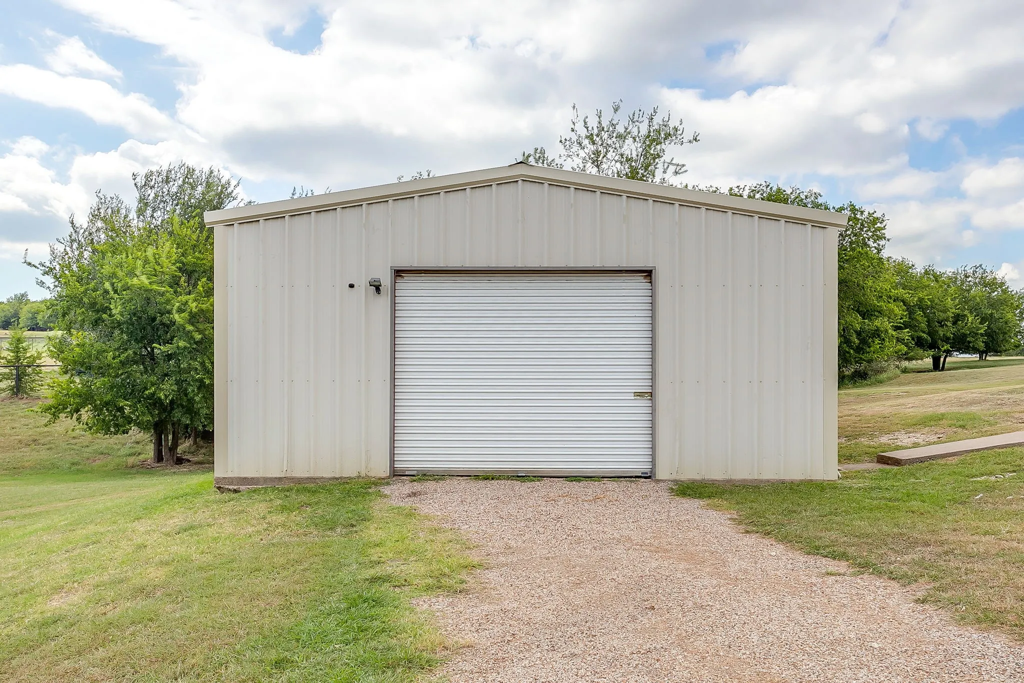 Brick exterior home with an attached garage, a separate detached garage, stone retaining wall, and a gravel driveway