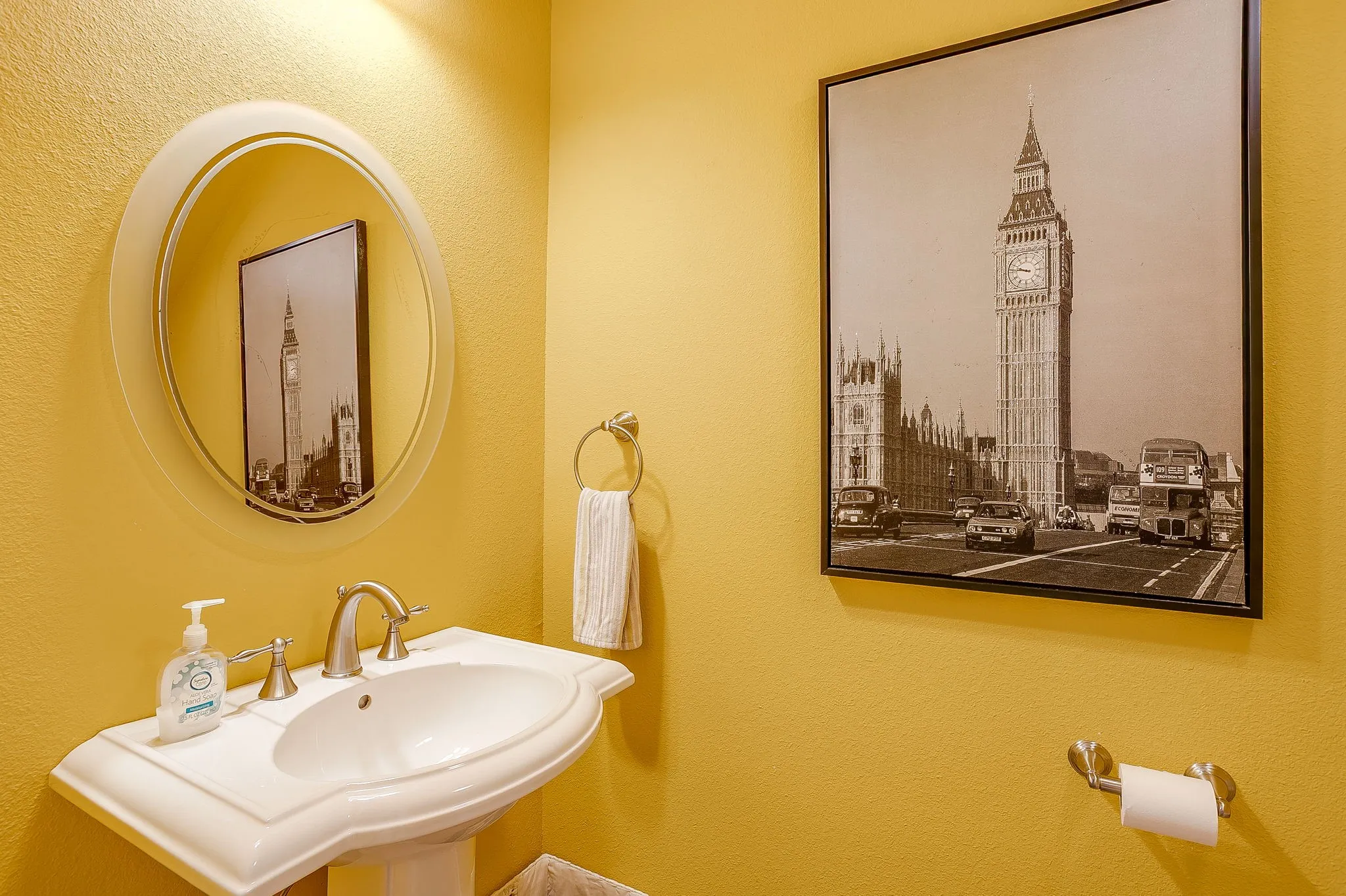 Upstairs half bath. Pedestal sink with a brushed nickel faucet, an oval wall-mounted mirror, and a wall-mounted light fixture