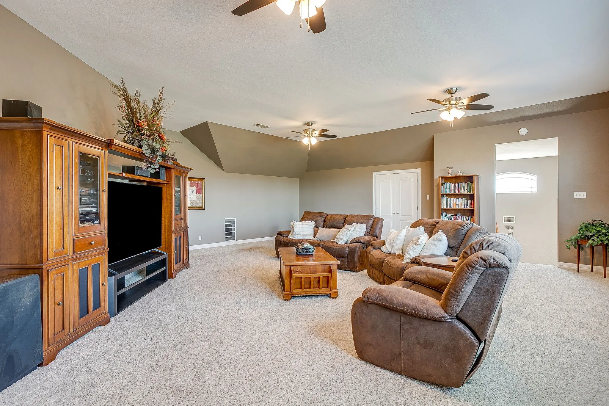 Carpeted room featuring multiple ceiling fans, recessed lighting, and an arched entry