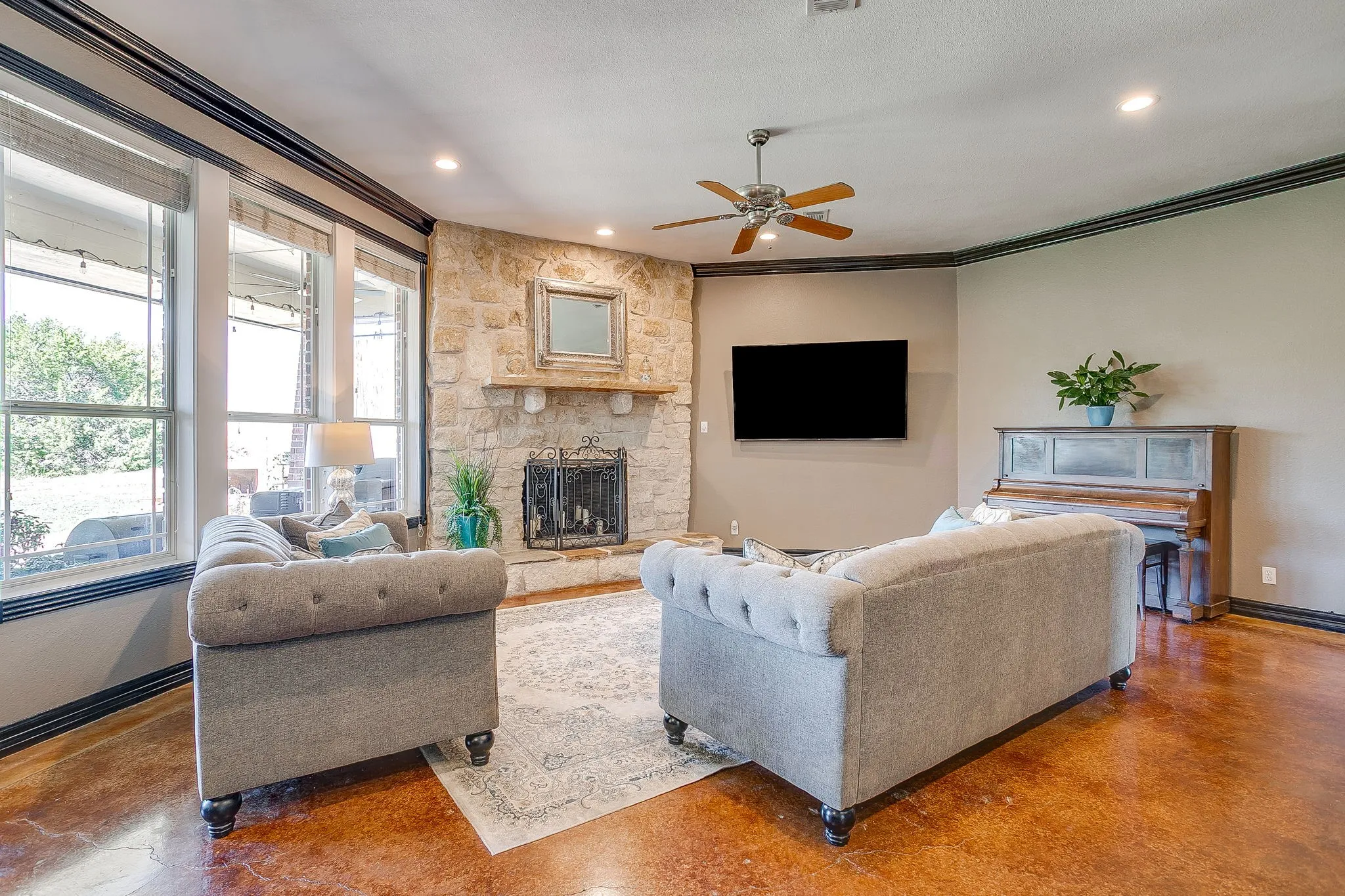 Stone-clad fireplace with mantel, recessed lighting, ceiling fan, wood-finish flooring, and multiple windows