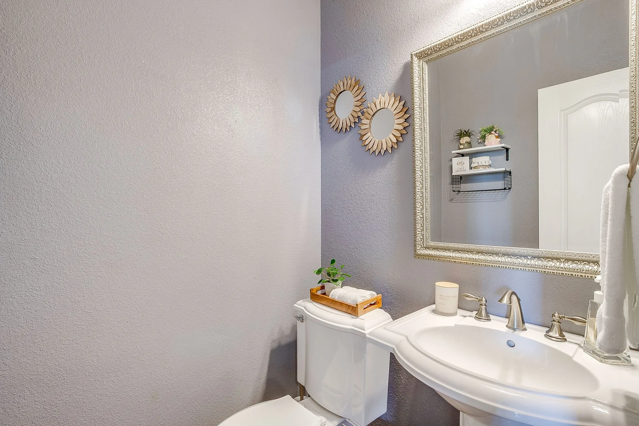 Downstairs half bath. Pedestal sink with brushed nickel faucet, framed mirror, and built-in wall shelving