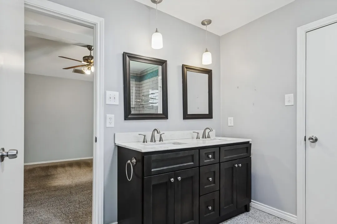 Dual vanity with white countertop, dark wood-finish cabinetry, and brushed nickel hardware