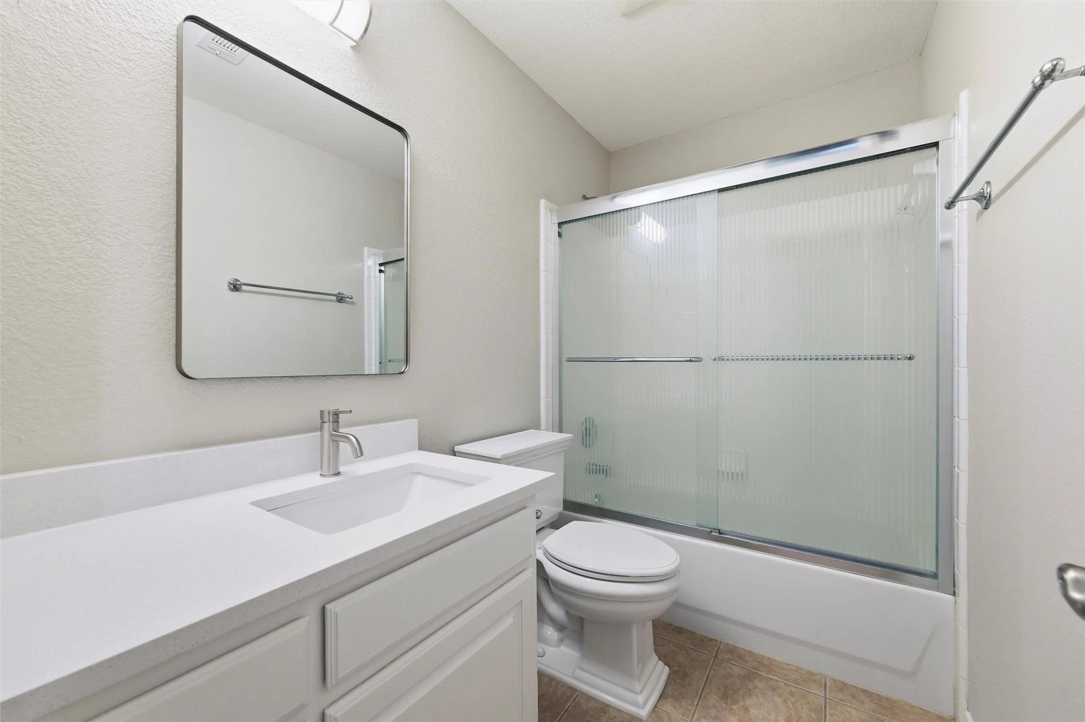 Updated hall bathroom featuring a refreshed vanity with new granite countertop, modern mirror, updated fixtures, and a tub/shower combination with sliding glass enclosure.
