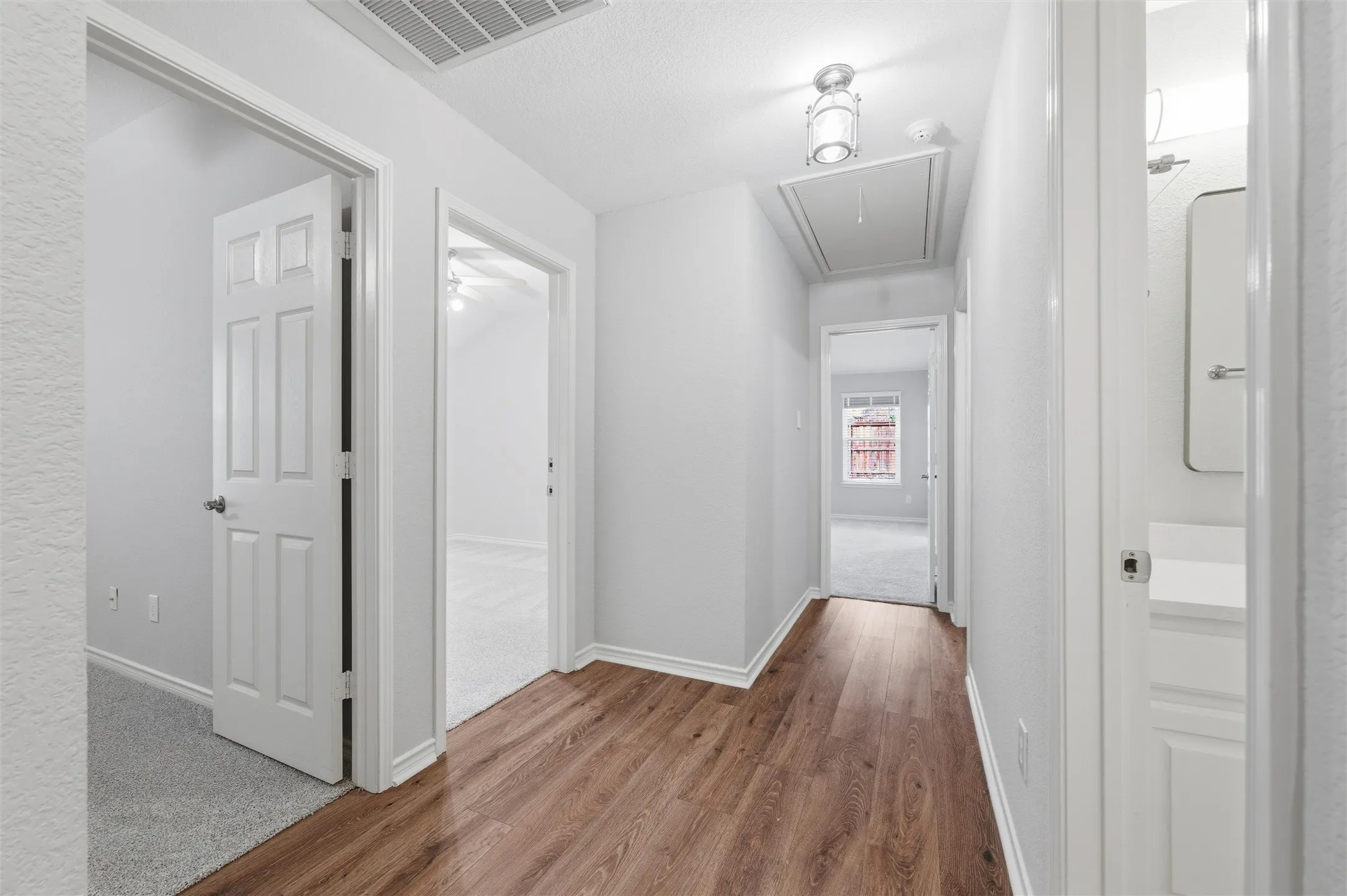 Well-lit hallway featuring new luxury vinyl plank flooring and fresh neutral finishes, connecting the main living areas to the private bedrooms.