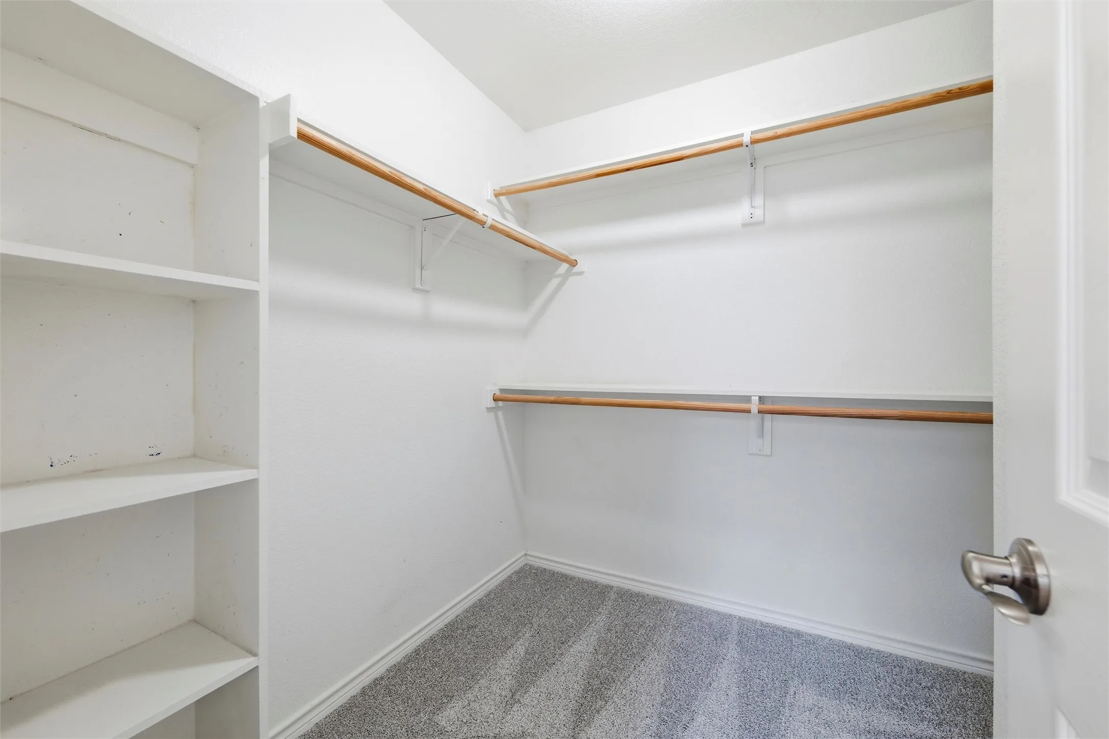 Walk-in primary closet offering built-in shelving, dual hanging rods, and ample storage space.