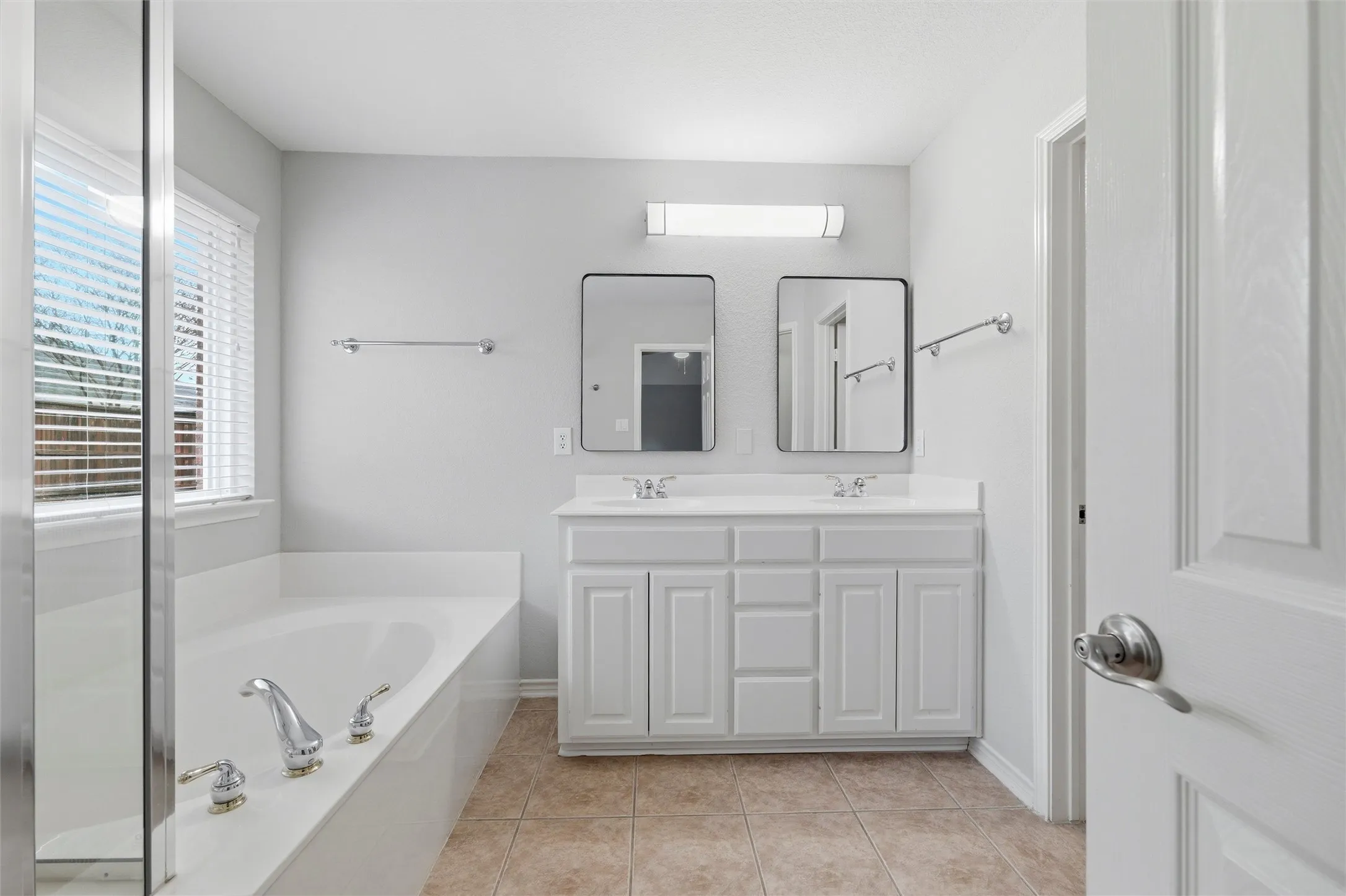 Primary bath featuring painted cabinetry, dual sinks, updated mirrors, and clean, timeless finishes.