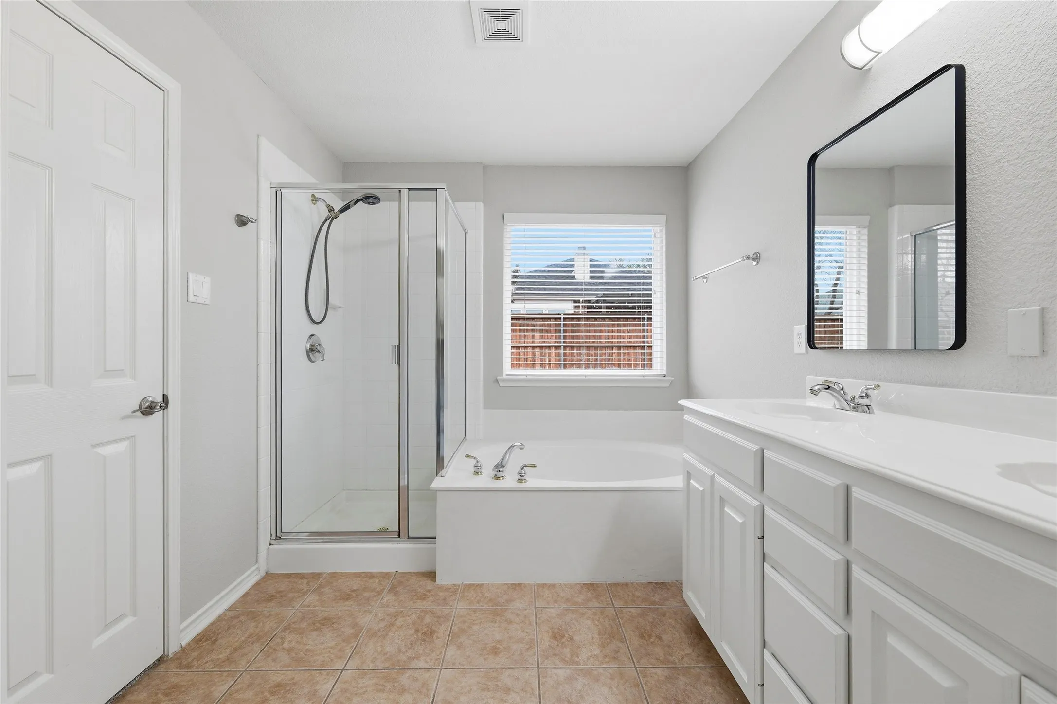 The Primary bathroom offers a soaking tub, separate glass-enclosed shower, and tile flooring.