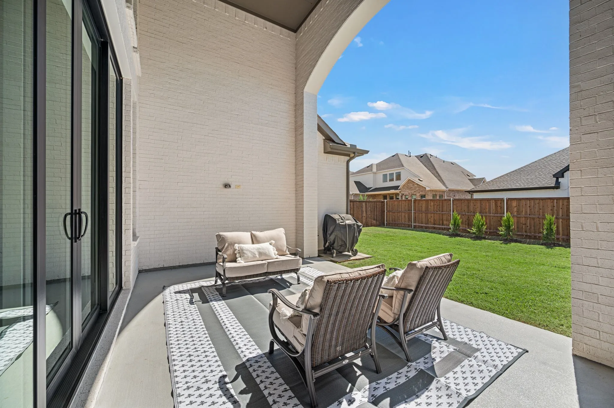 Covered patio with a painted concrete surface, white brick exterior, and a spacious grassy yard