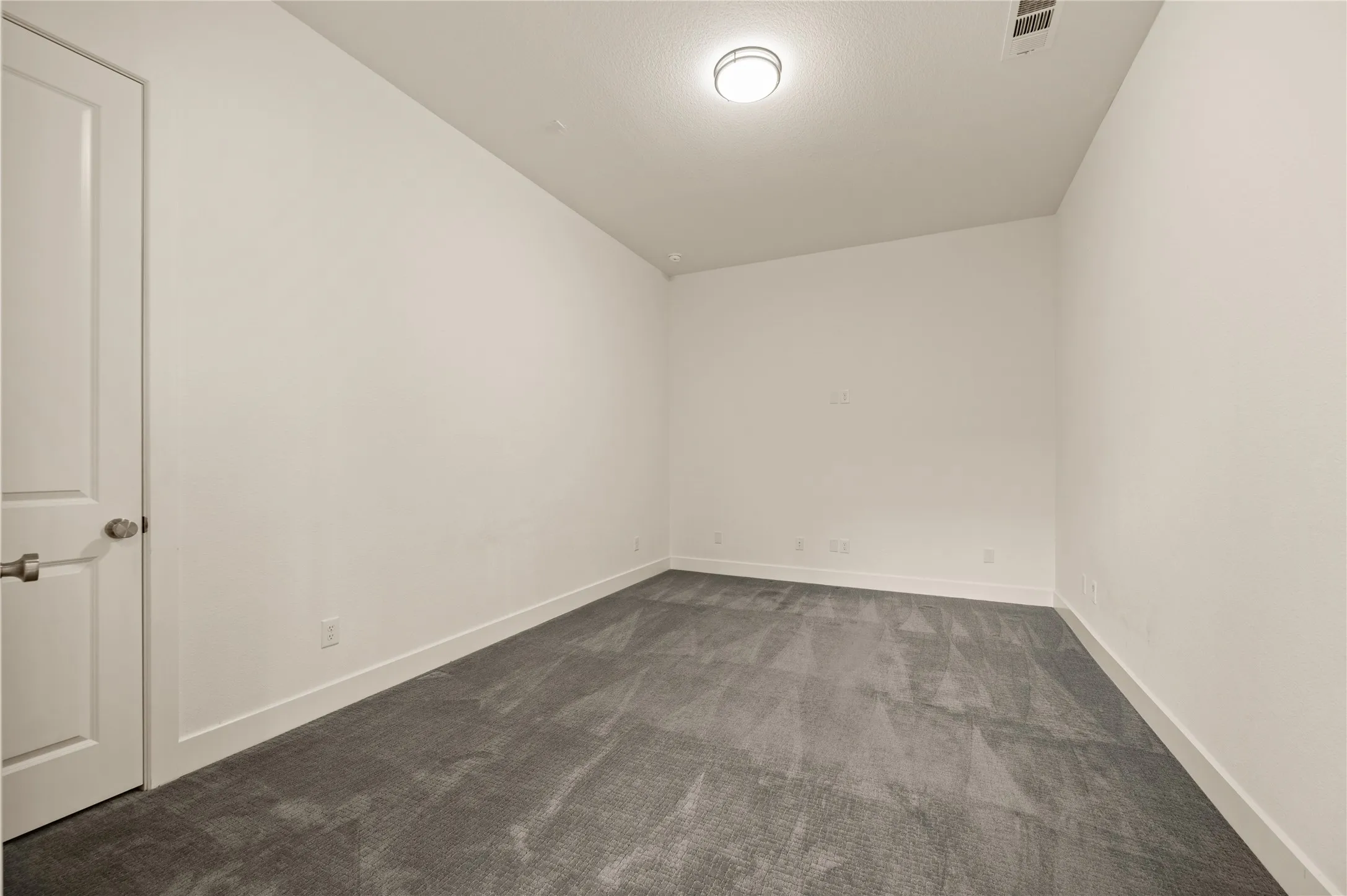 White paneled door with brushed nickel hardware, neutral wall paint, recessed lighting, and gray patterned carpeting