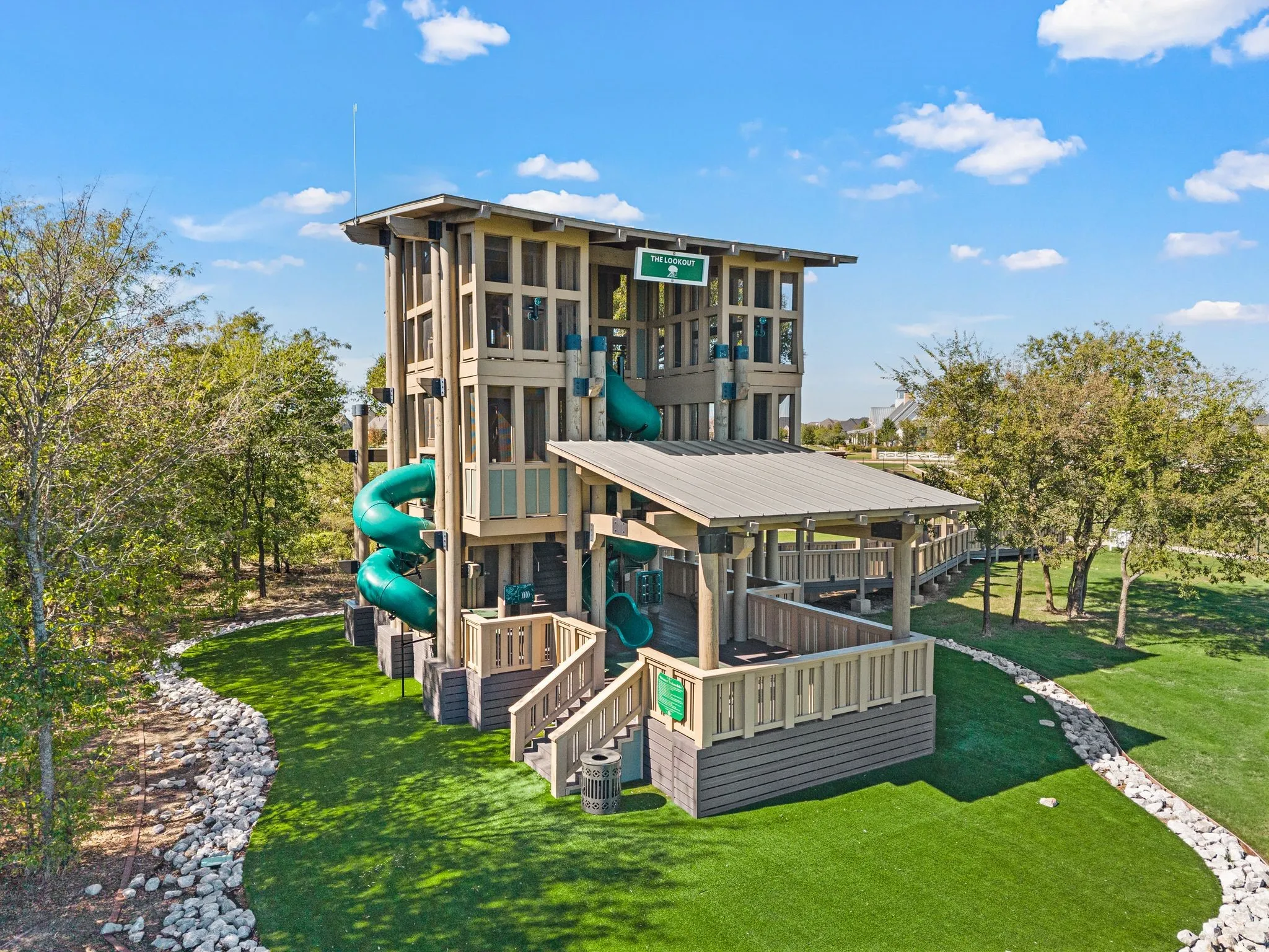 Multi-level recreational structure featuring multiple slides, a covered deck, and an elevated walkway