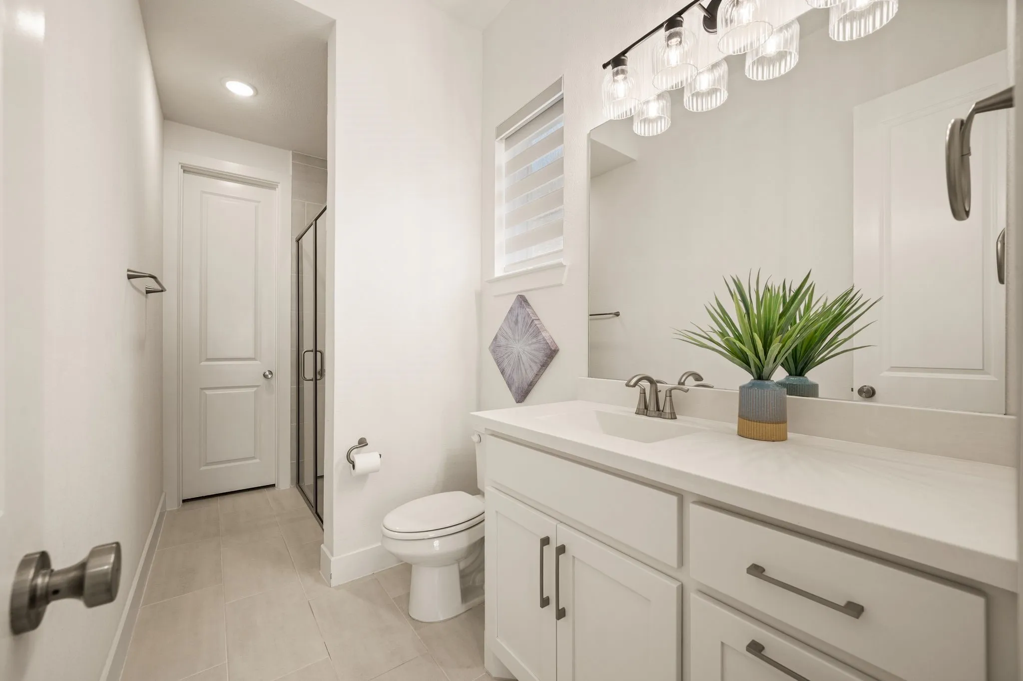 White vanity with a solid surface countertop, undermount sink, and contemporary hardware