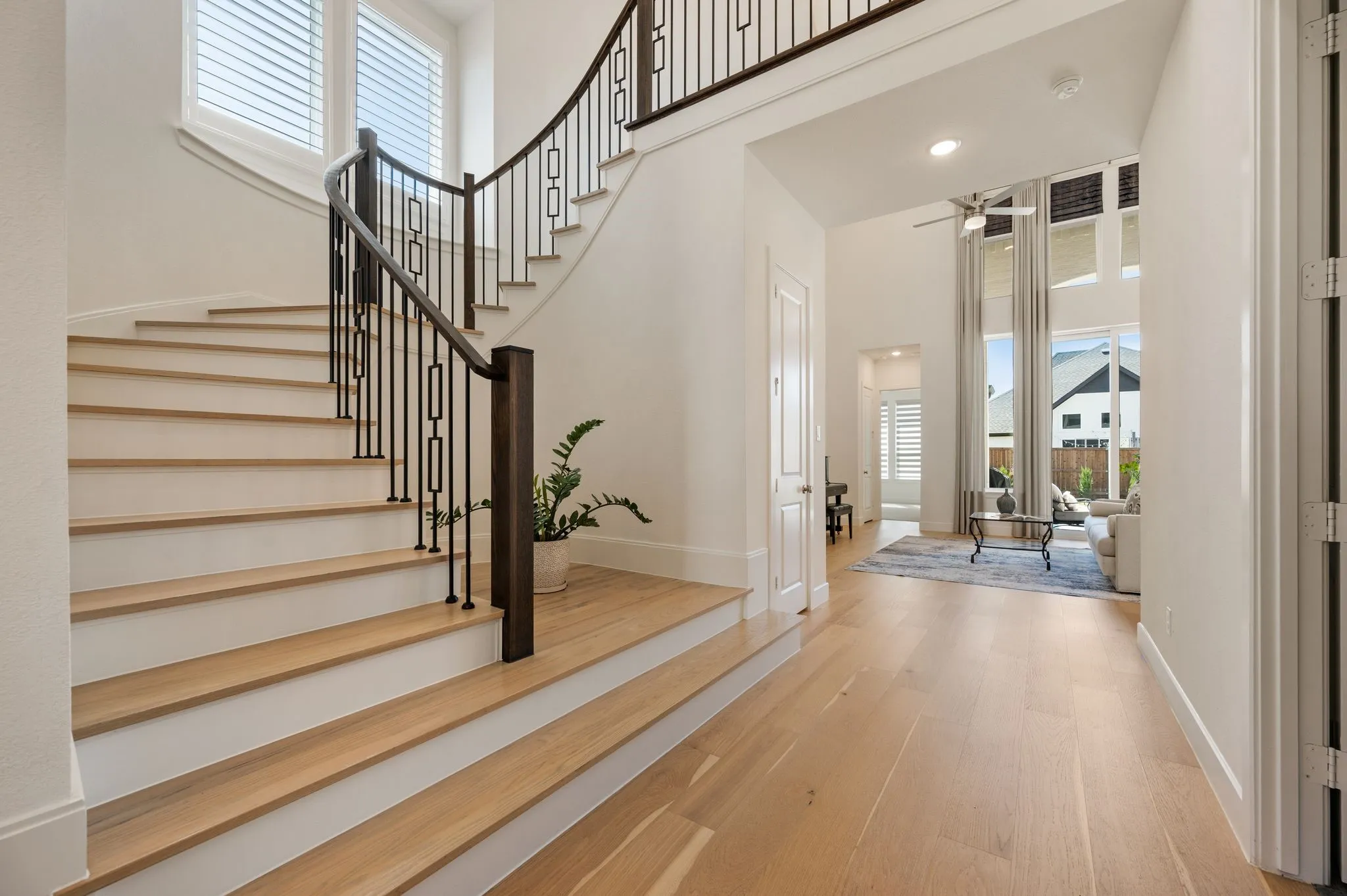 Curved staircase with wood-finish treads and risers, black metal balusters, and a dark wood-finish newel post