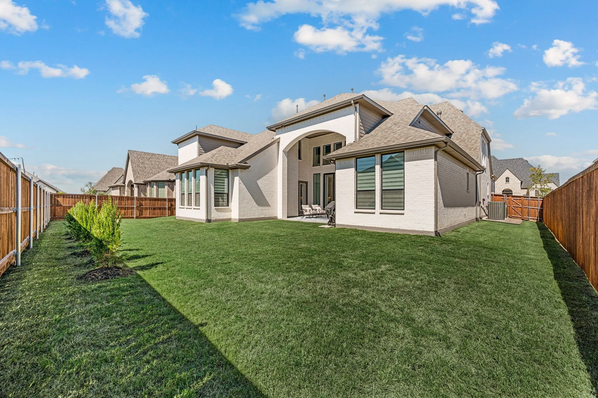 Expansive green lawn with a white brick and stucco exterior