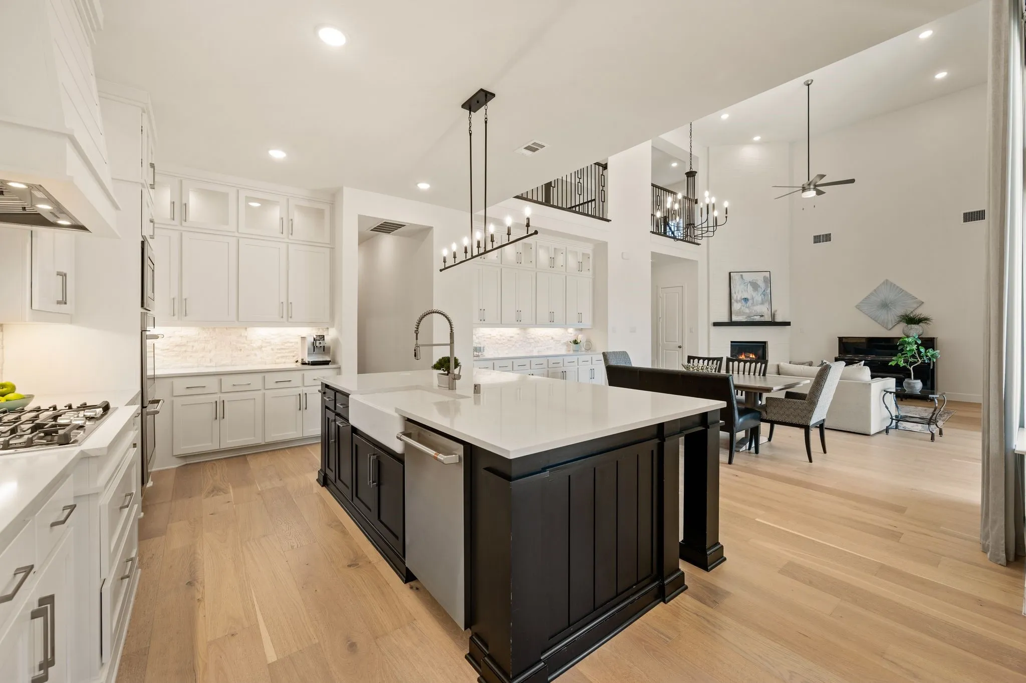 Gourmet kitchen with a large central island, white cabinetry, integrated appliances, and wood-finish flooring