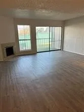 Spacious living area with wood-finish flooring throughout, abundant natural light from sliding glass doors and transom windows, and a fireplace with dark surround detail