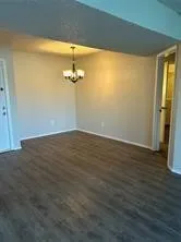 Wood-finish flooring throughout, light-toned wall paint, and a classic chandelier