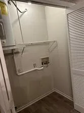 Utility area featuring wood-finish flooring, a water heater, and a bi-fold louvered door