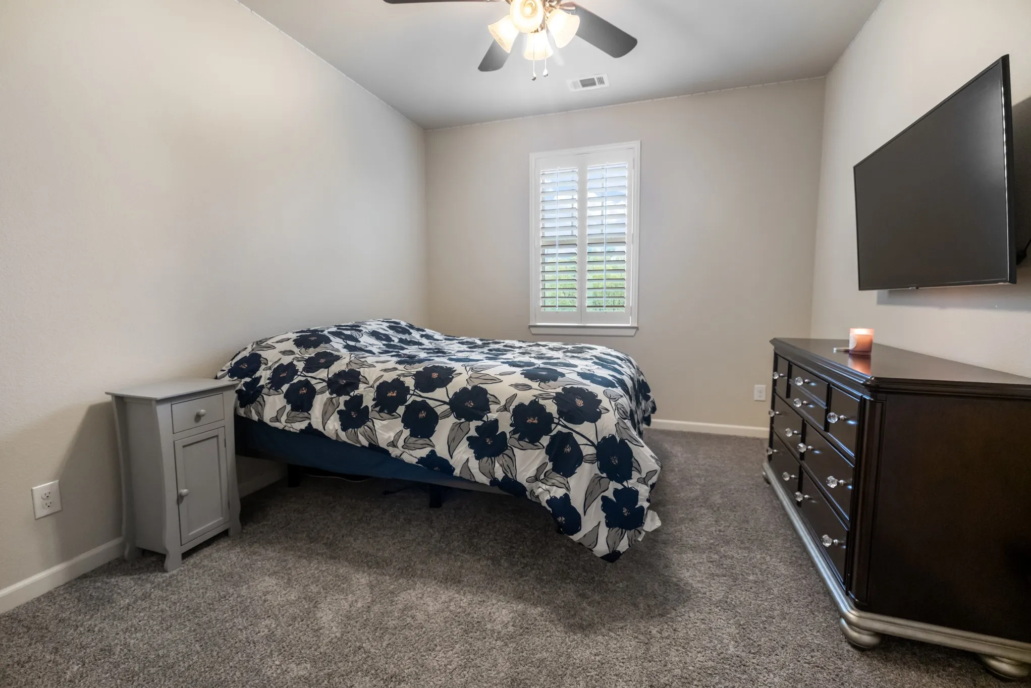 Upstairs. Plush gray carpeting, white plantation shutters, and a ceiling fan with integrated lighting