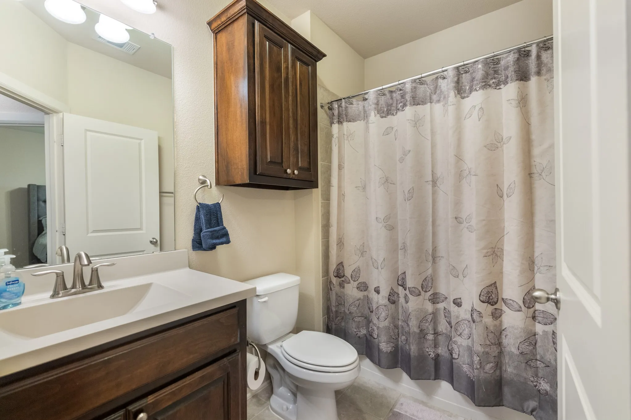 Vanity with an integrated sink and brushed nickel faucet, wood-finish cabinetry, and an overhead lighting fixture