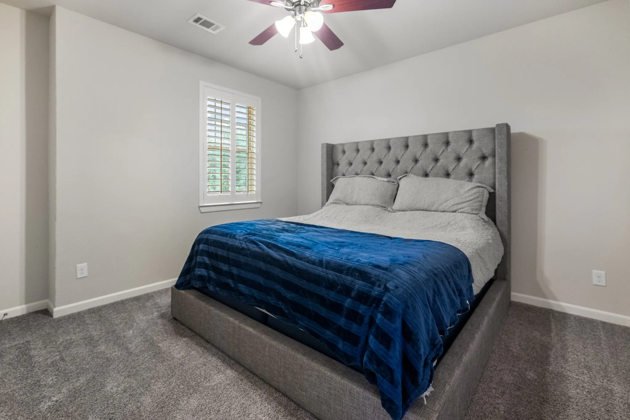 Bedroom three. Upstairs. Wall-to-wall carpeting, window with plantation shutters, ceiling fan, and neutral wall tones