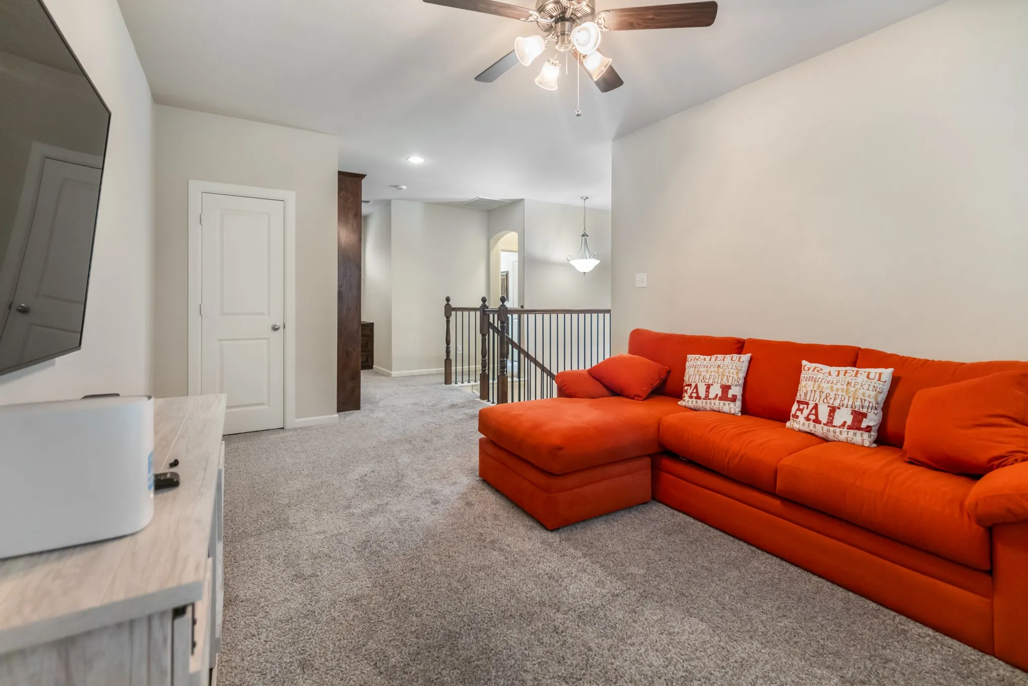 Upstairs. Recessed lighting, ceiling fan with light fixture, carpet flooring, white interior door, and dark wood newel posts