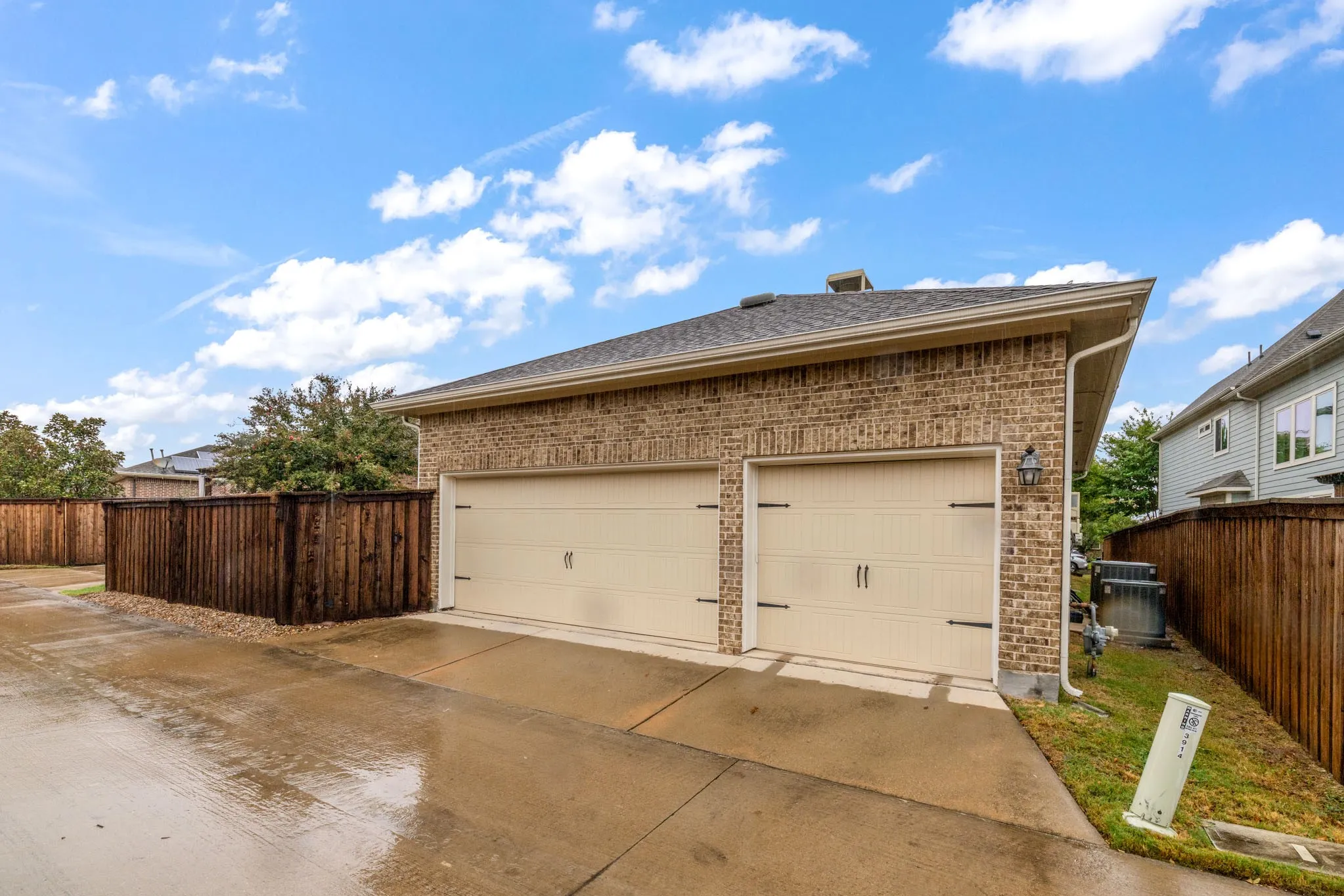 Brick exterior two-car garage with light-colored doors and dark hardware