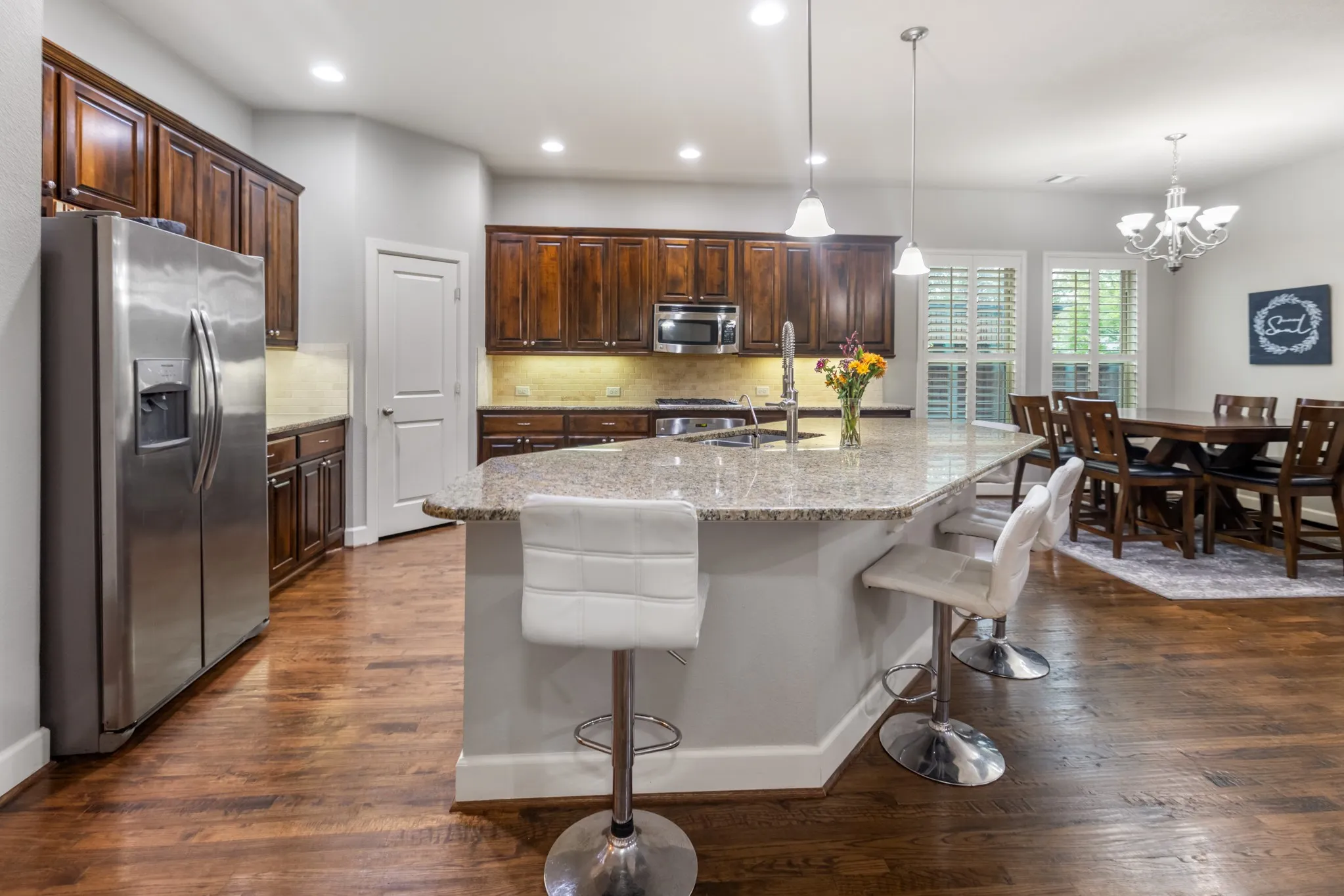 Open-concept kitchen with wood-finish flooring, a large island with a stone countertop, and dark wood cabinetry