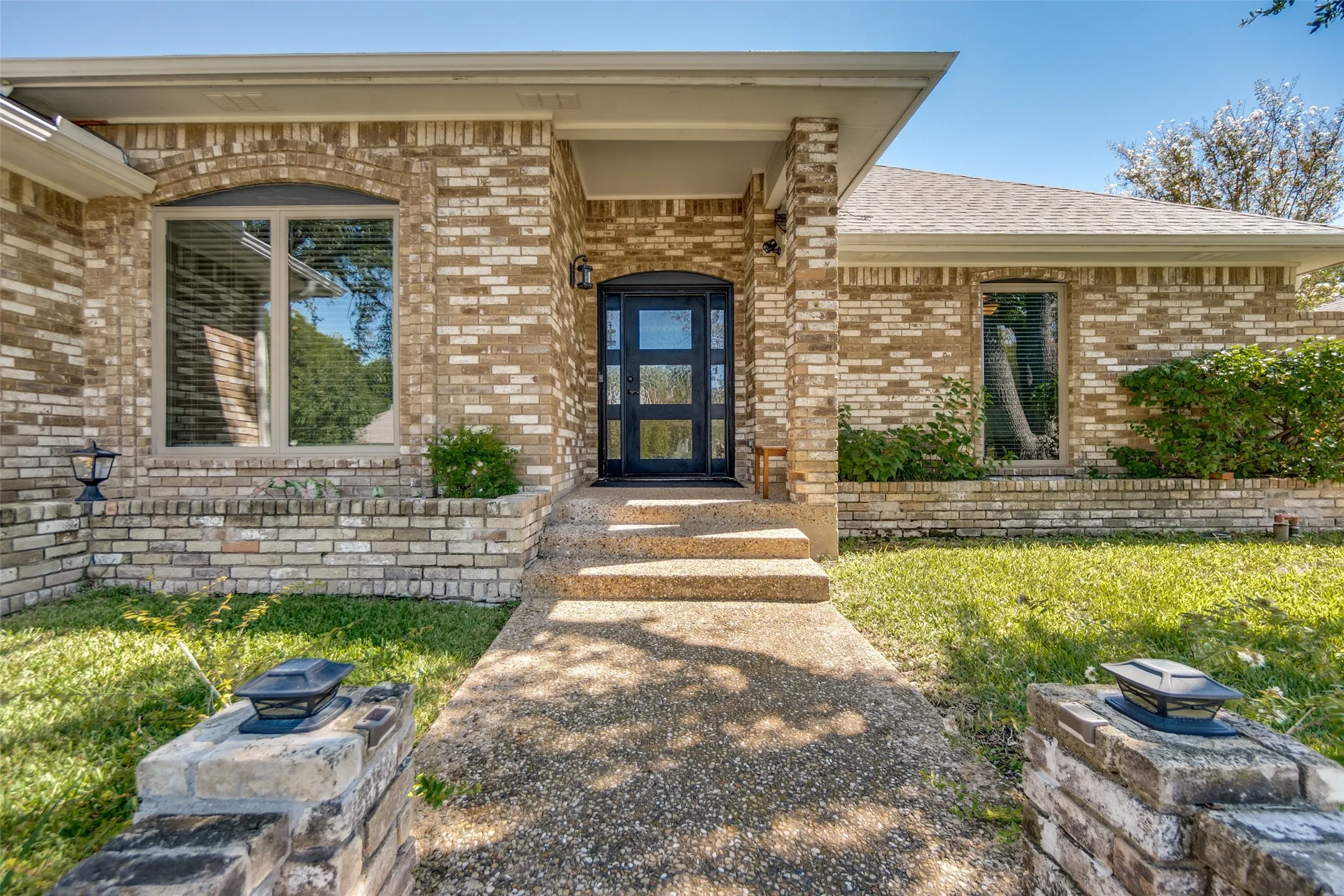 Brick exterior with a covered entry, arched window, and a modern glass-paneled door