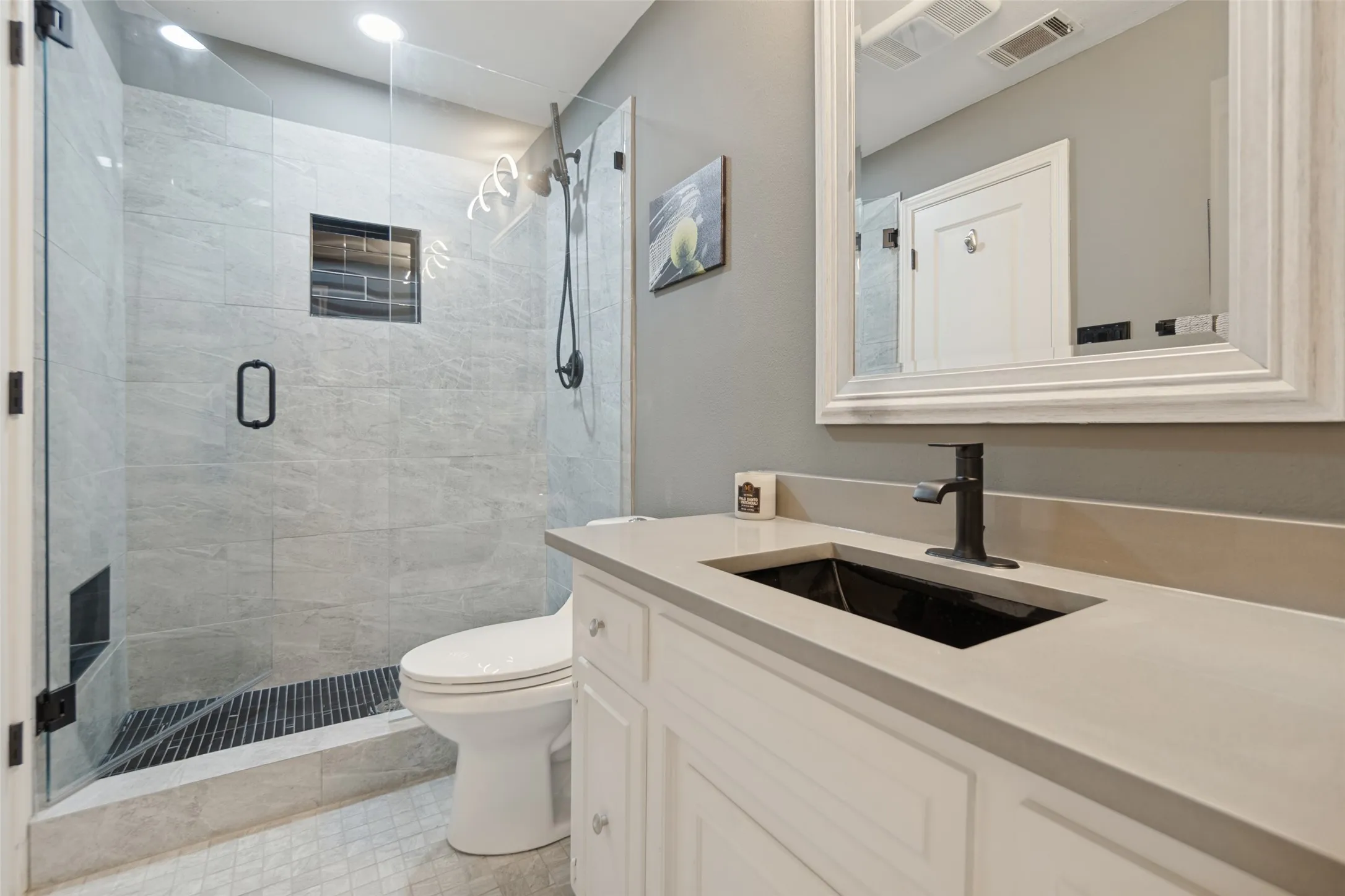 Walk-in shower with clear glass enclosure and light-toned tile