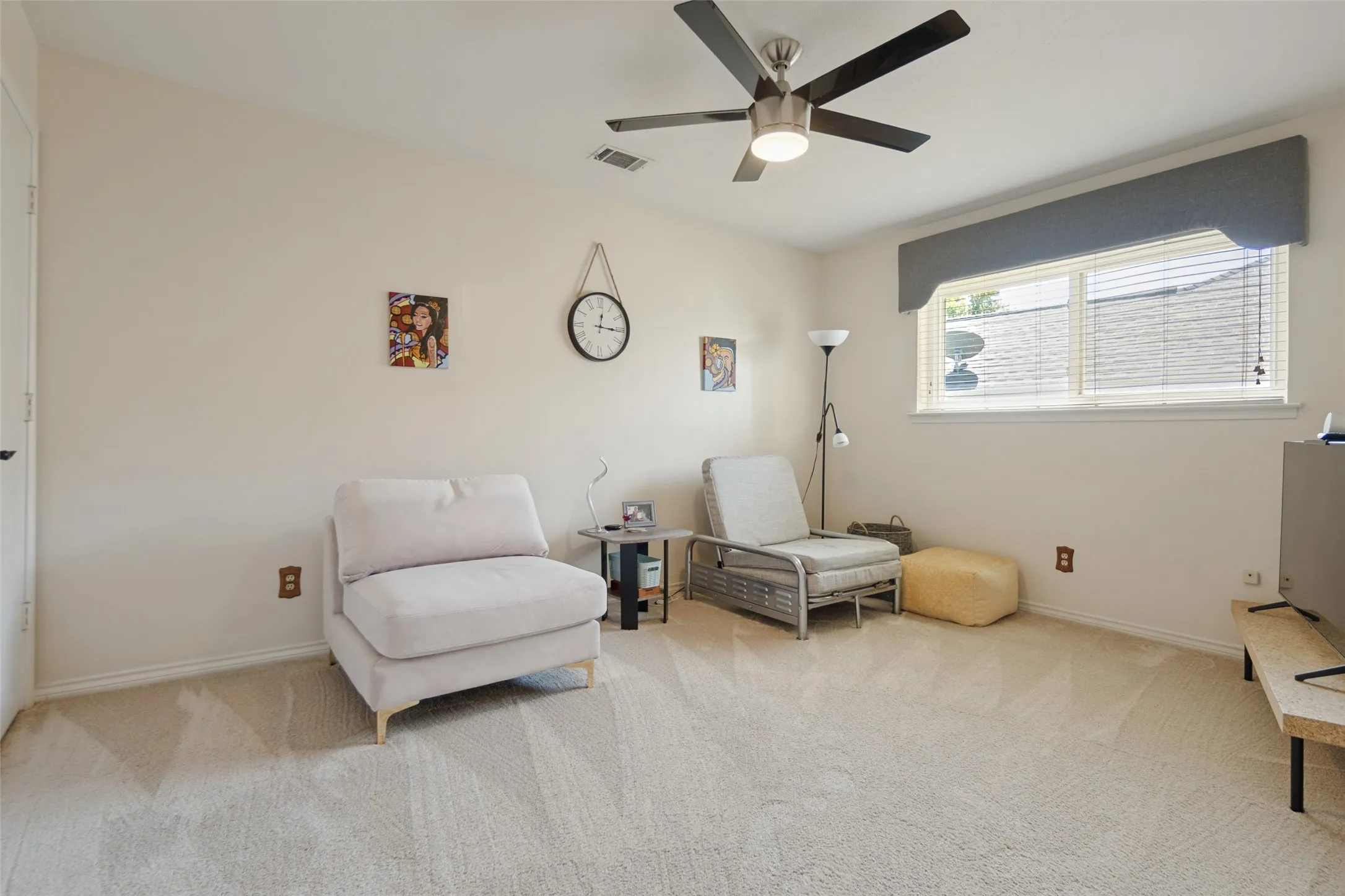 Neutral wall paint, ceiling fan, window with blinds, and light-toned carpeting