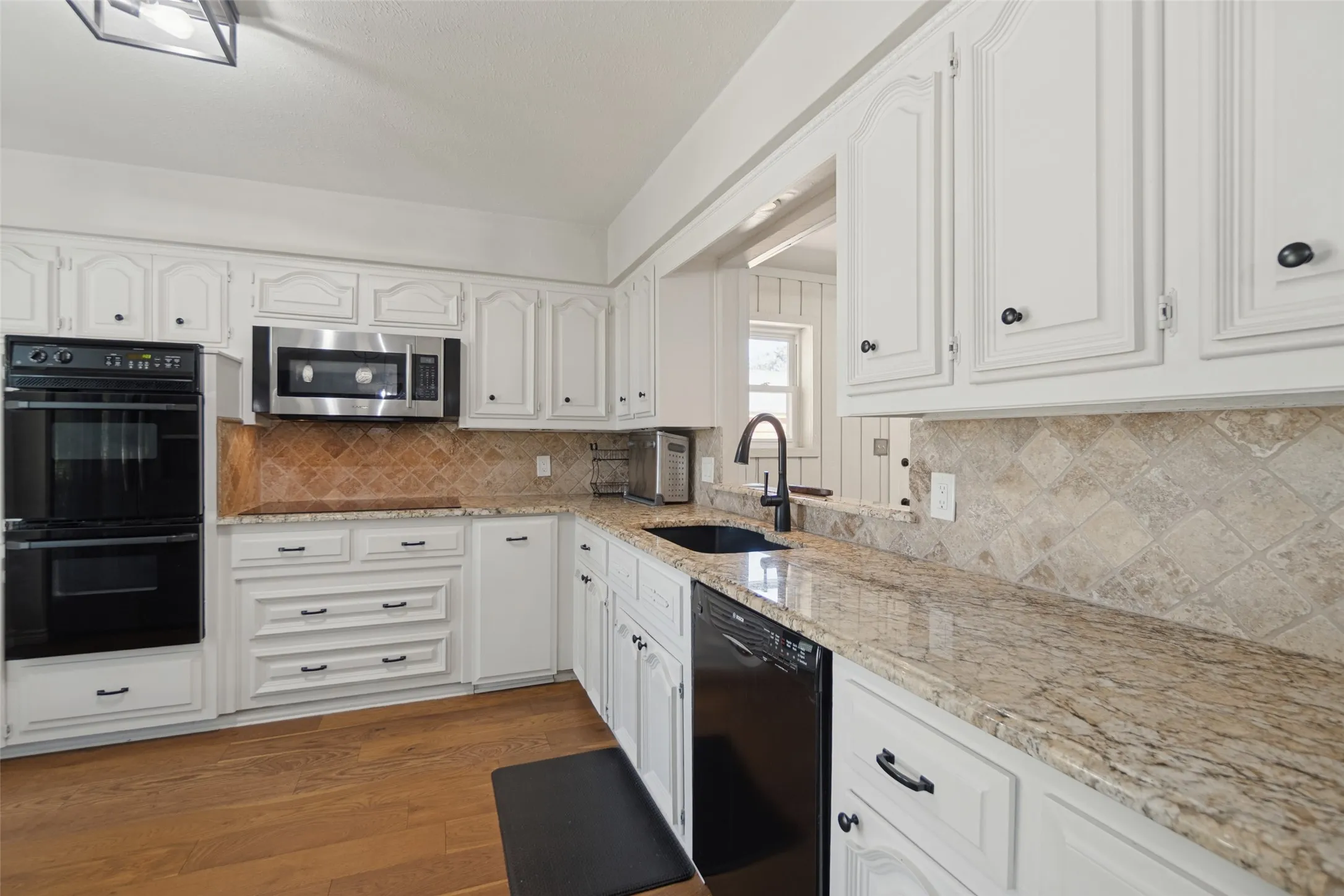 Kitchen featuring white cabinetry, granite countertops, double wall ovens, a built-in microwave, and wood-finish flooring