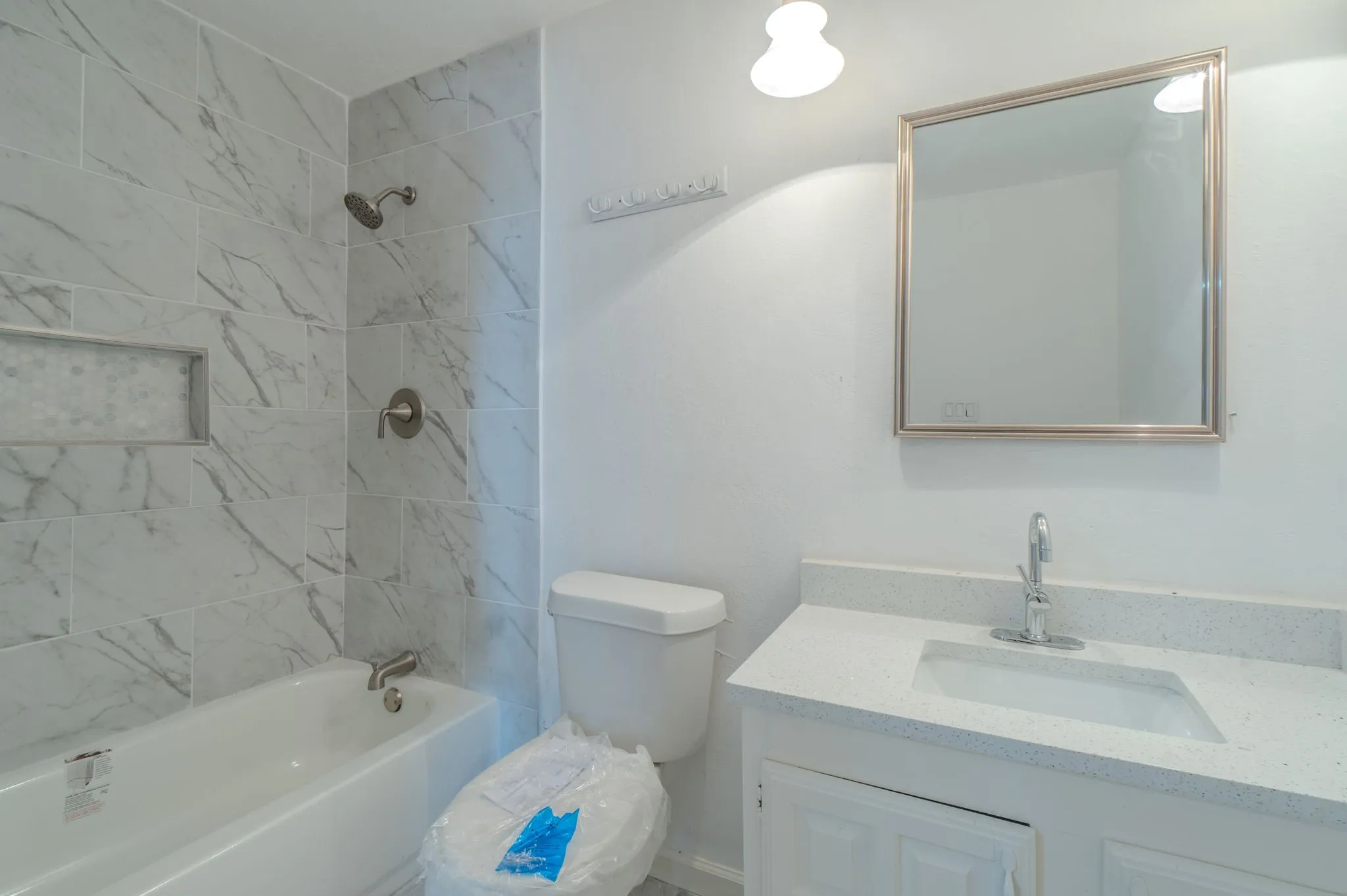 Tub-shower combination featuring large format wall tile with a decorative recessed niche