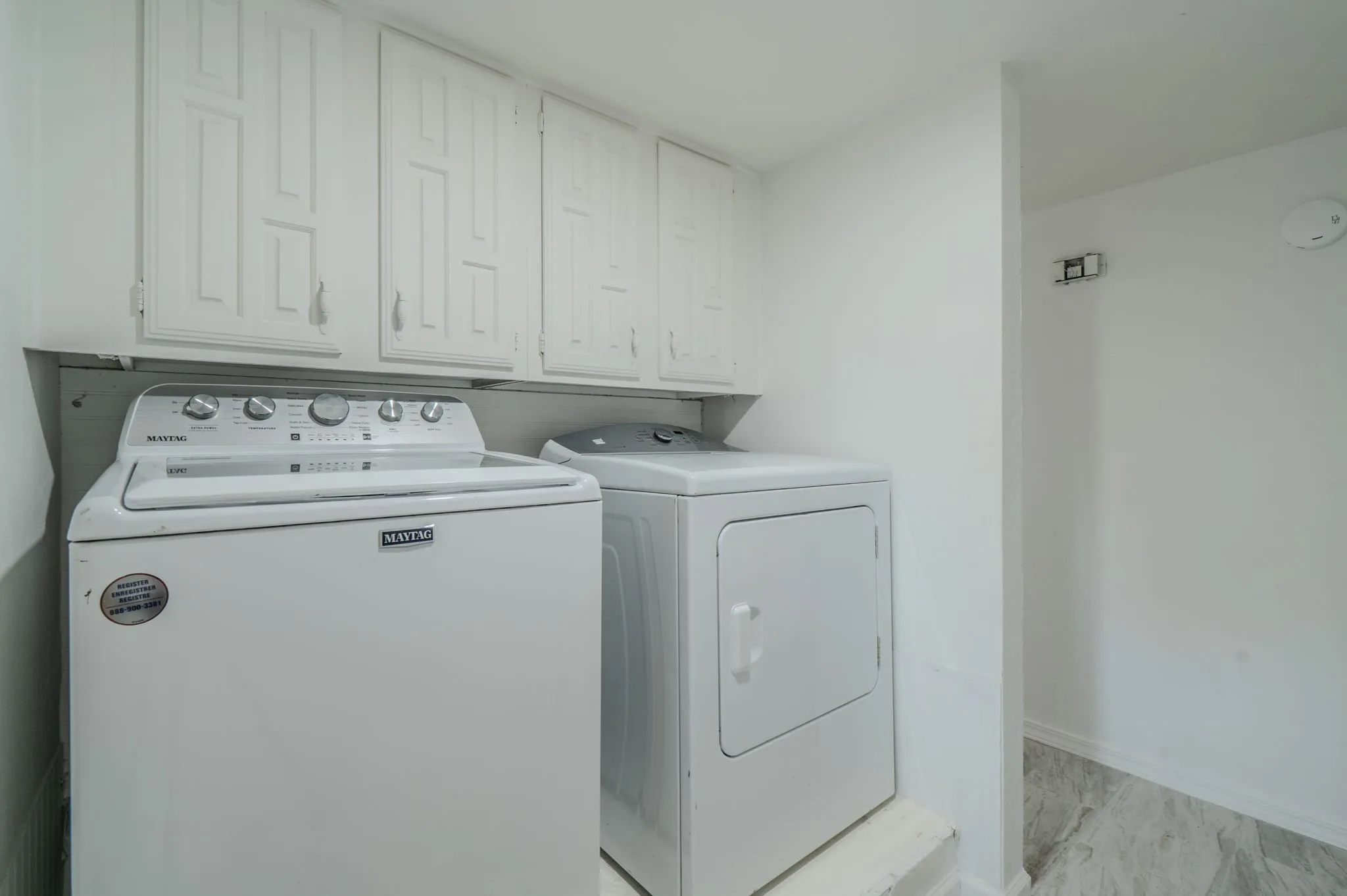 Laundry area featuring white cabinetry, a built-in shelf, and light-toned flooring