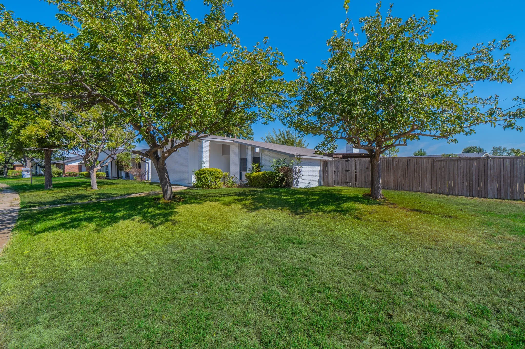 Expansive lawn with mature trees and privacy fencing