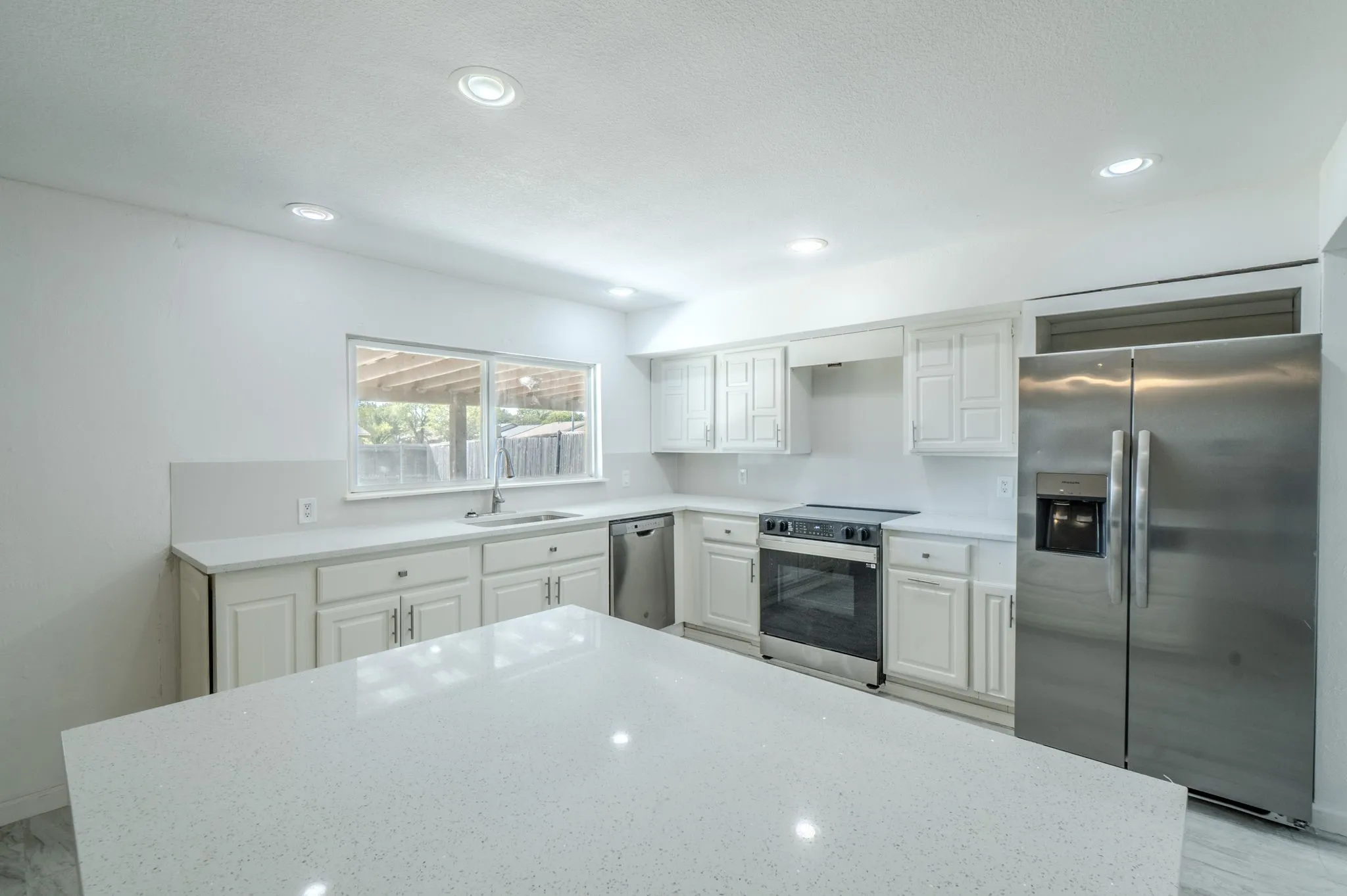 Kitchen featuring white cabinetry, light-toned countertops, recessed lighting, and stainless steel appliances