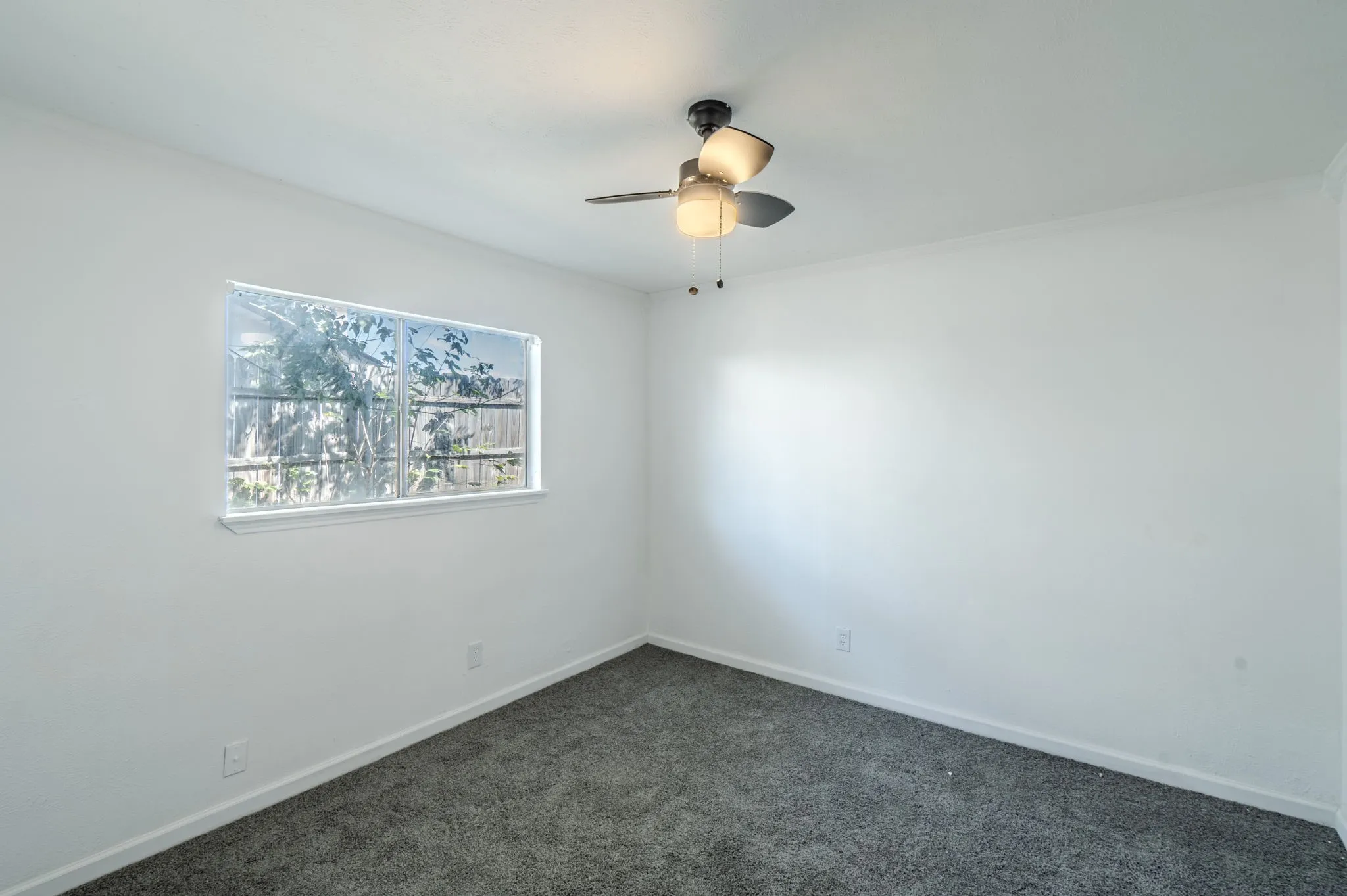 Recessed window, ceiling-mounted fan, and grey carpeting