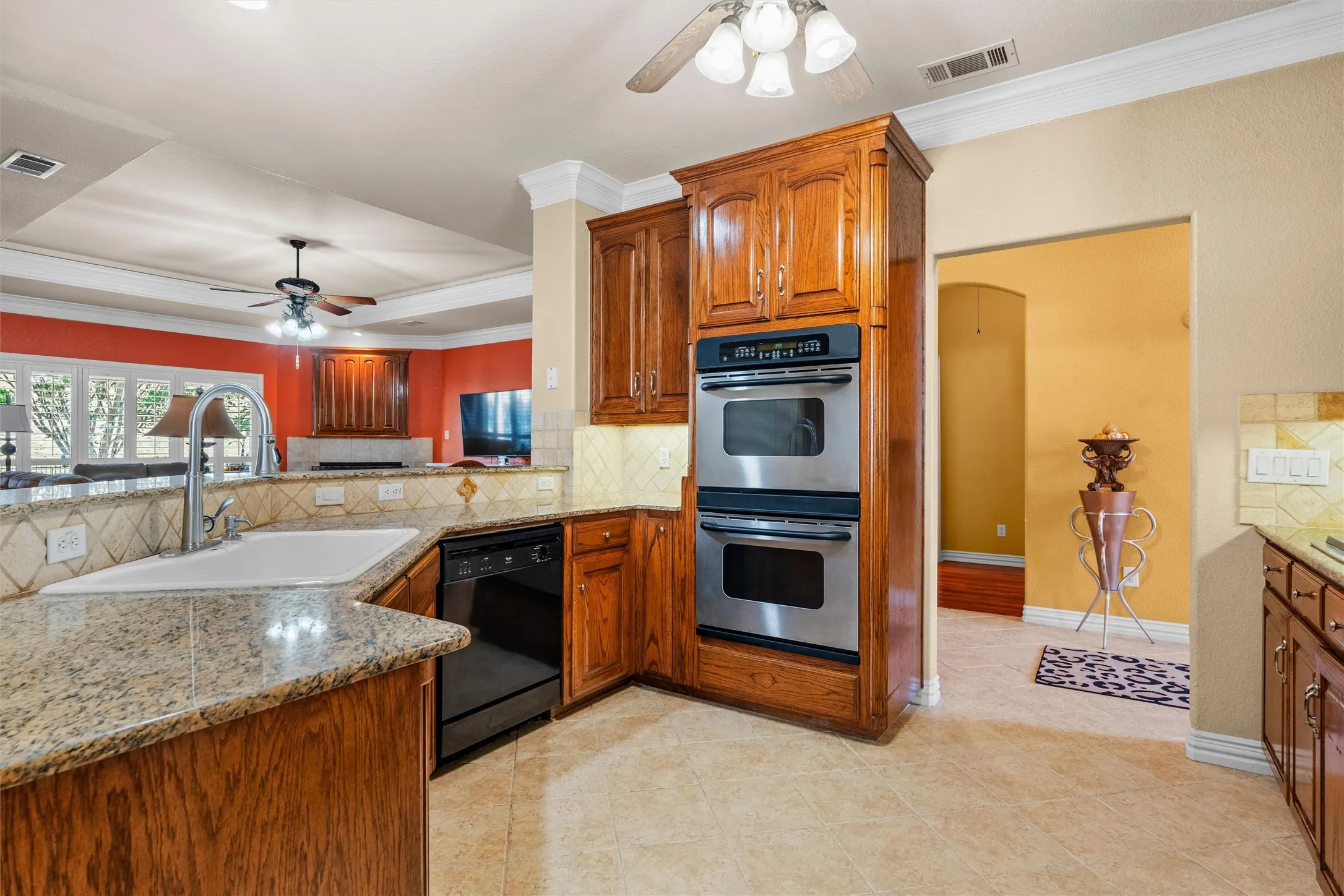 Kitchen with wood cabinetry, granite countertops, ceramic tile flooring, and stainless steel double wall ovens