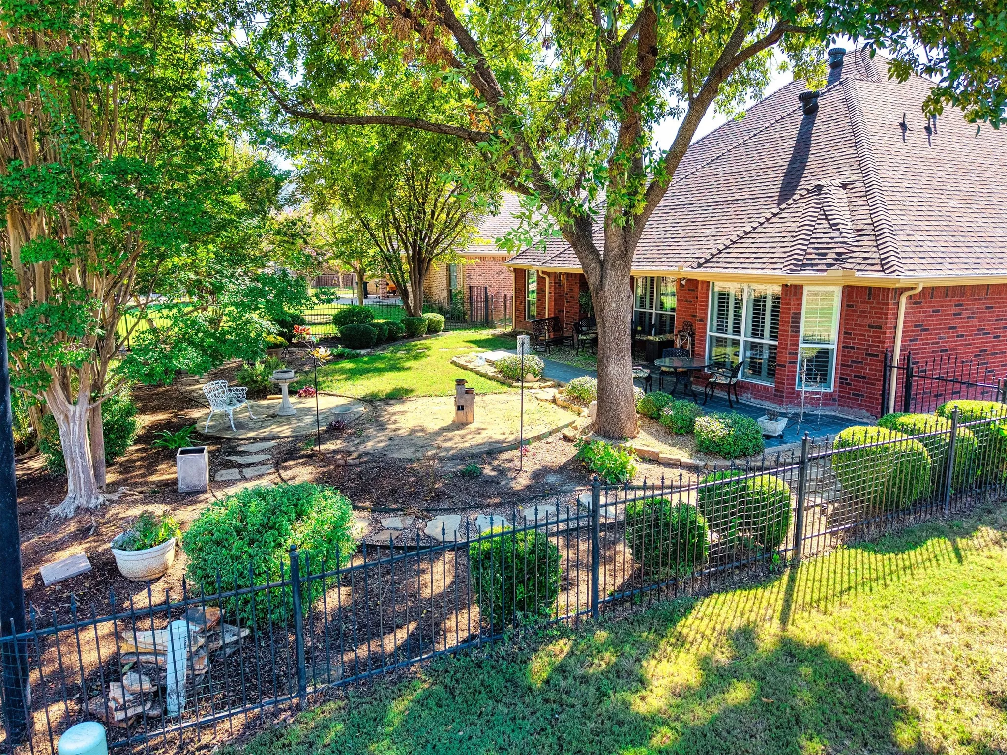 Brick exterior with multiple windows, a gabled roof, and black wrought iron fencing