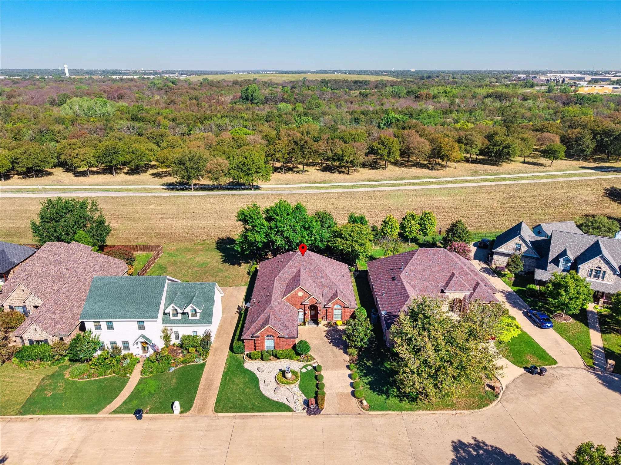 Brick exterior property with a multi-gabled roof, mature landscaping, and an attached driveway